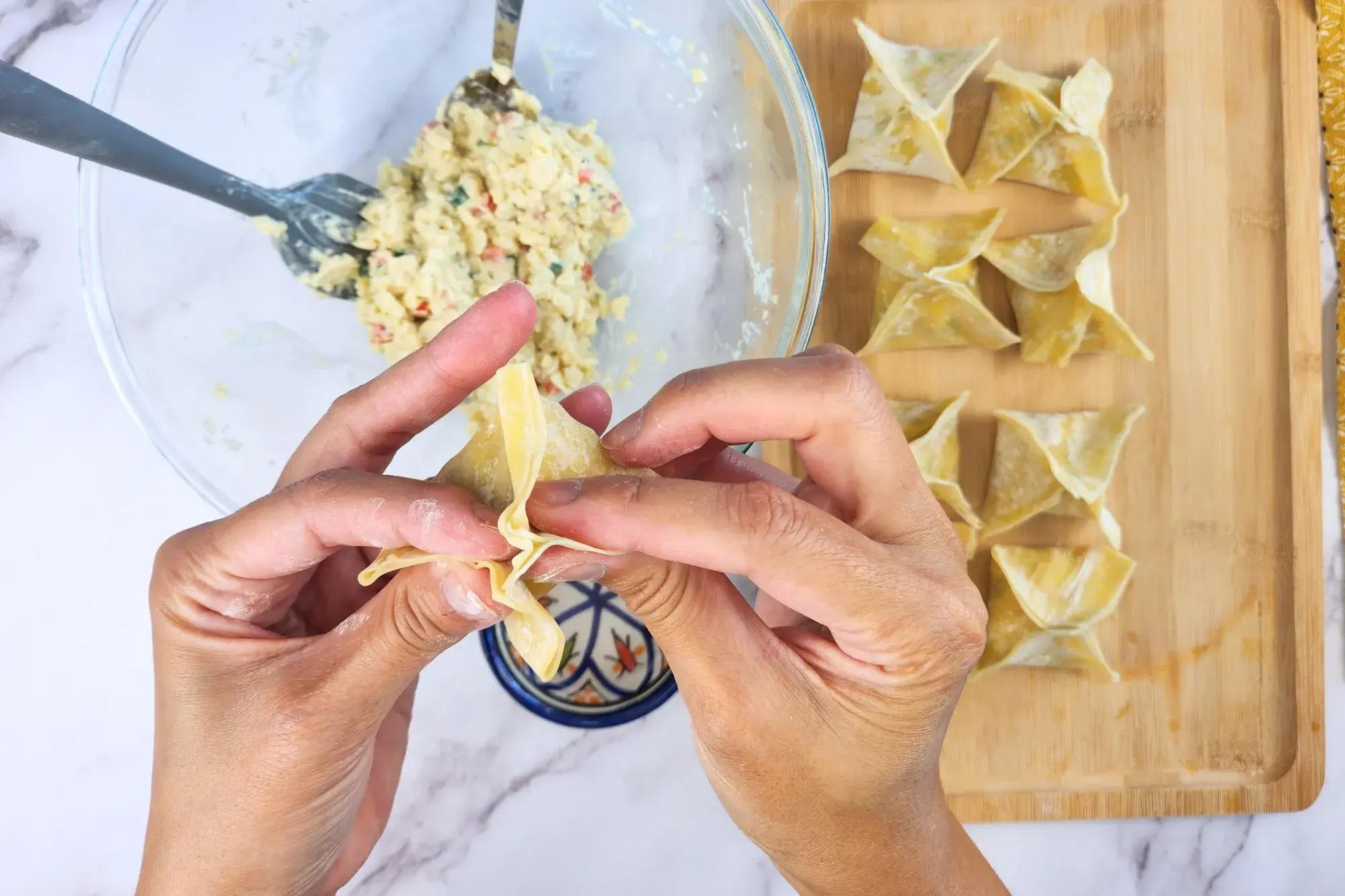 Two hands are sealing the wonton.