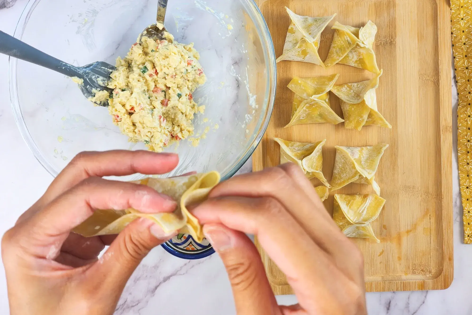 Two hands assemble the edges of wonton.
