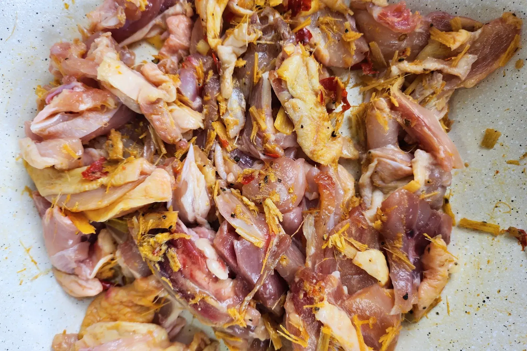 Uncooked chicken with lemongrass chili paste in a wok.