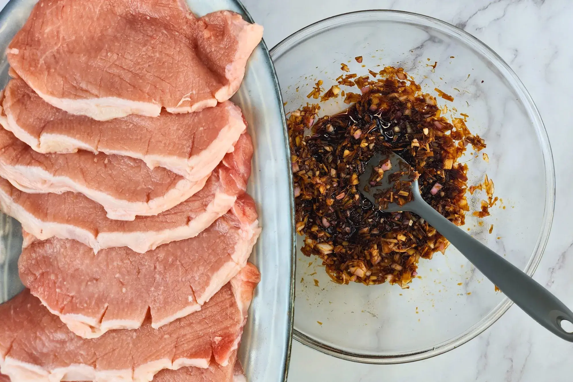 Uncooked pork chops next to a mixing bowl