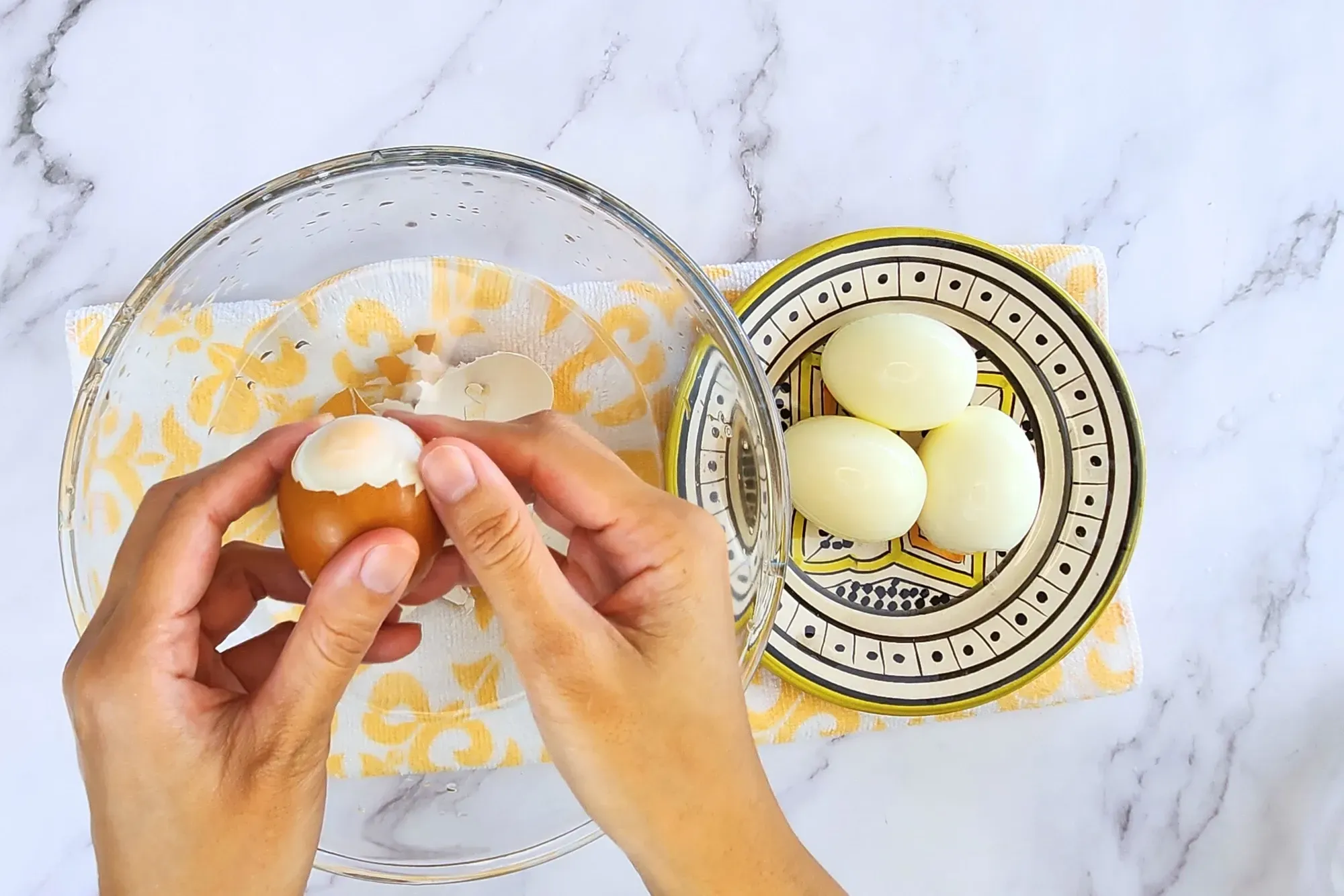 2 hands peeling hard boiled egg