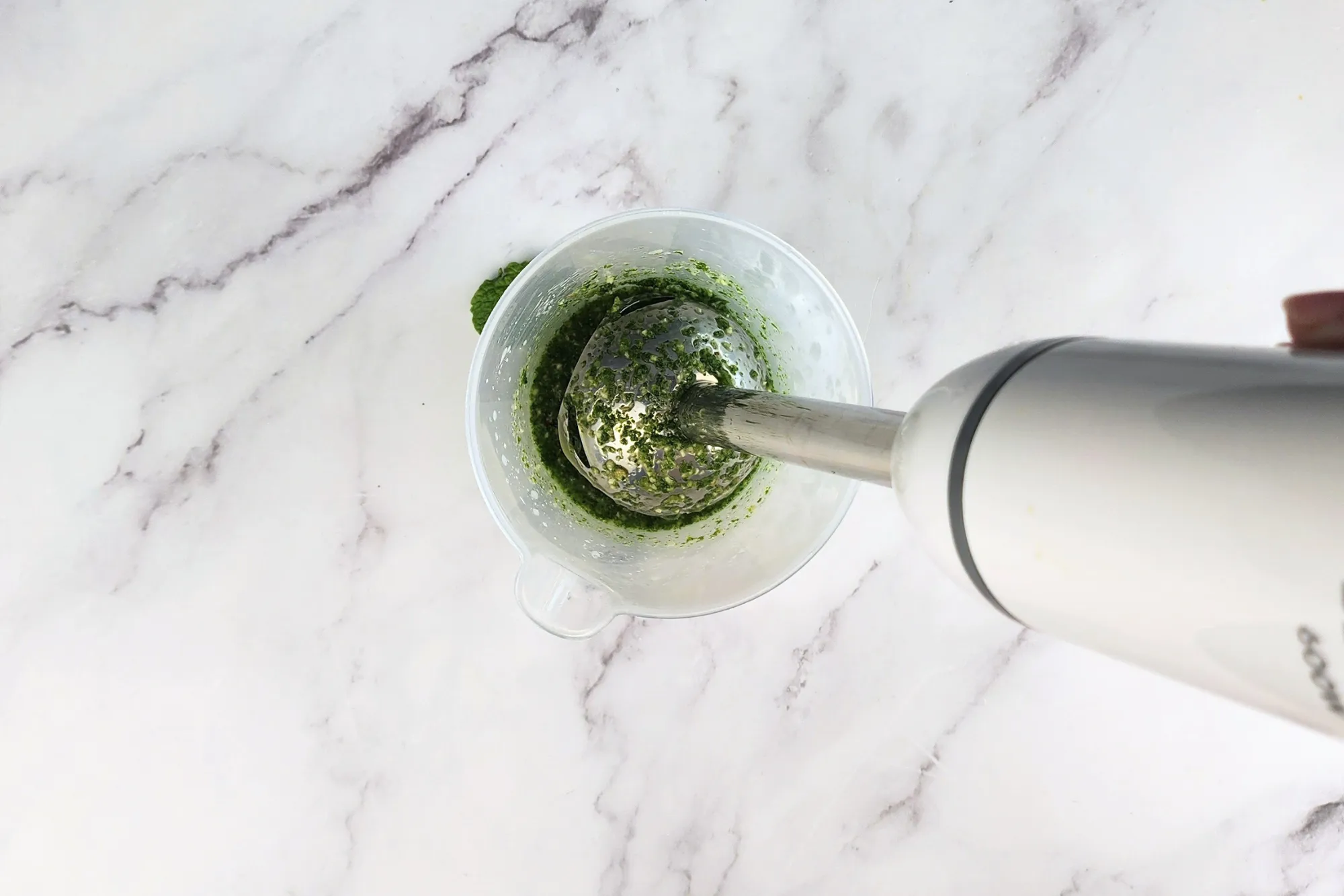 A blender is in a jar of green sauce.