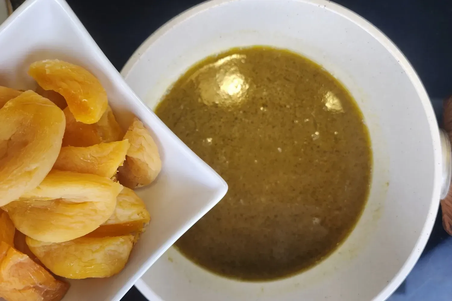 A bowl of boiled apricots above a pot with broth.