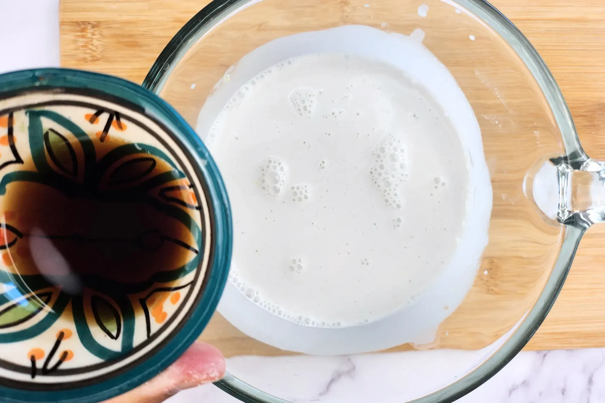 A bowl of fish sauce above a jar of coconut milk.