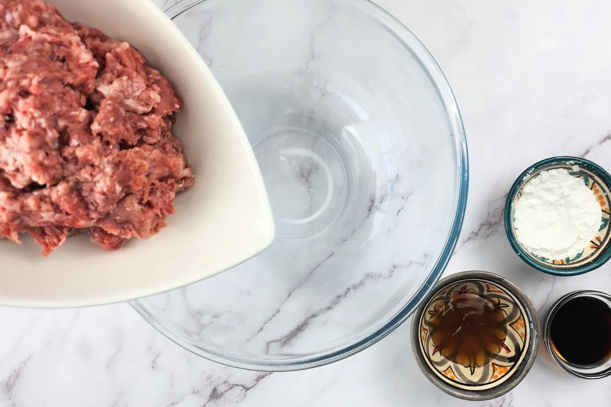A bowl of ground beef above an empty mixing bowl.
