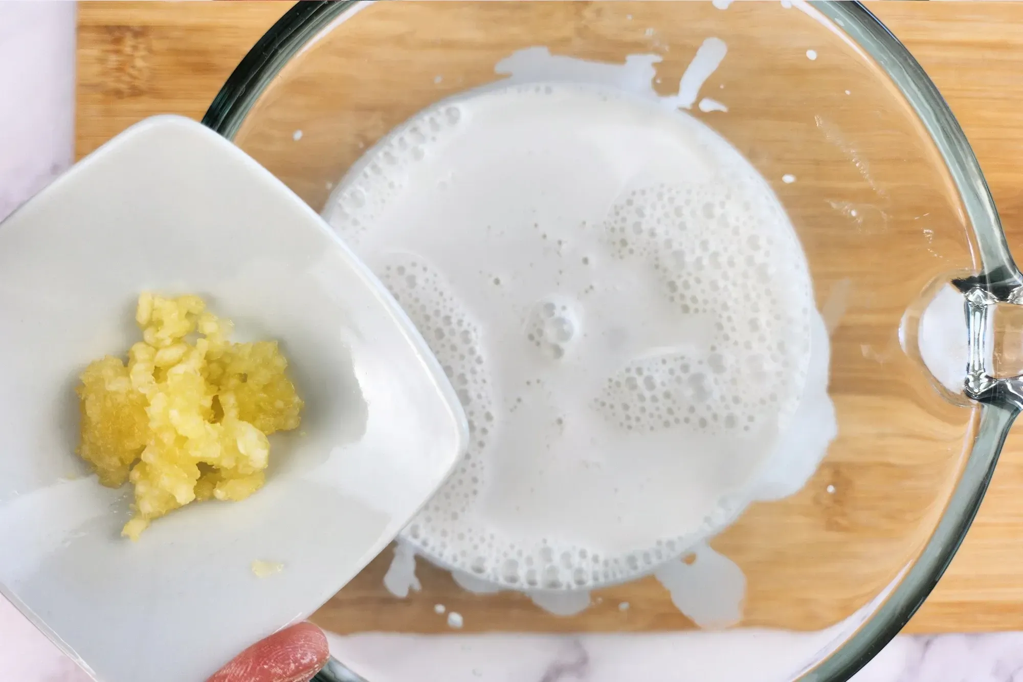 A bowl of minced ginger above a jar of coconut milk.