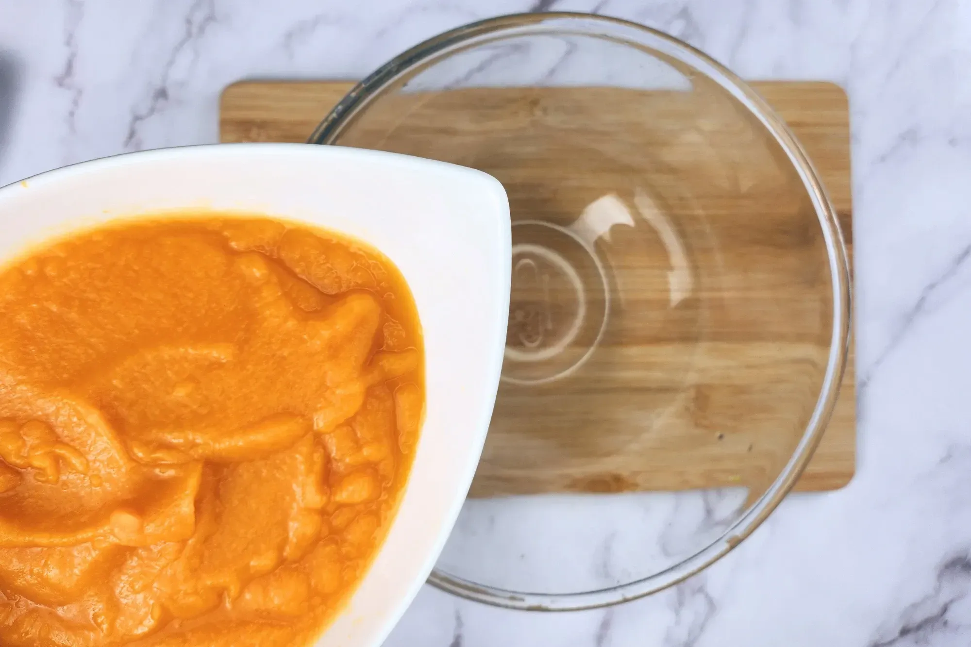 A bowl of pumpkin puree above an empty mixing bowl