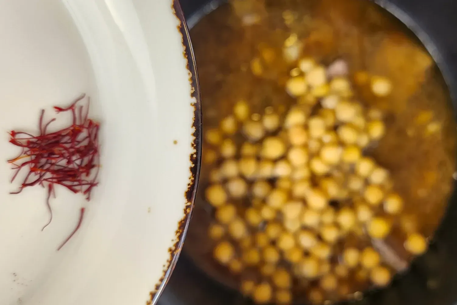 A bowl of saffron thread above a pot with meat.