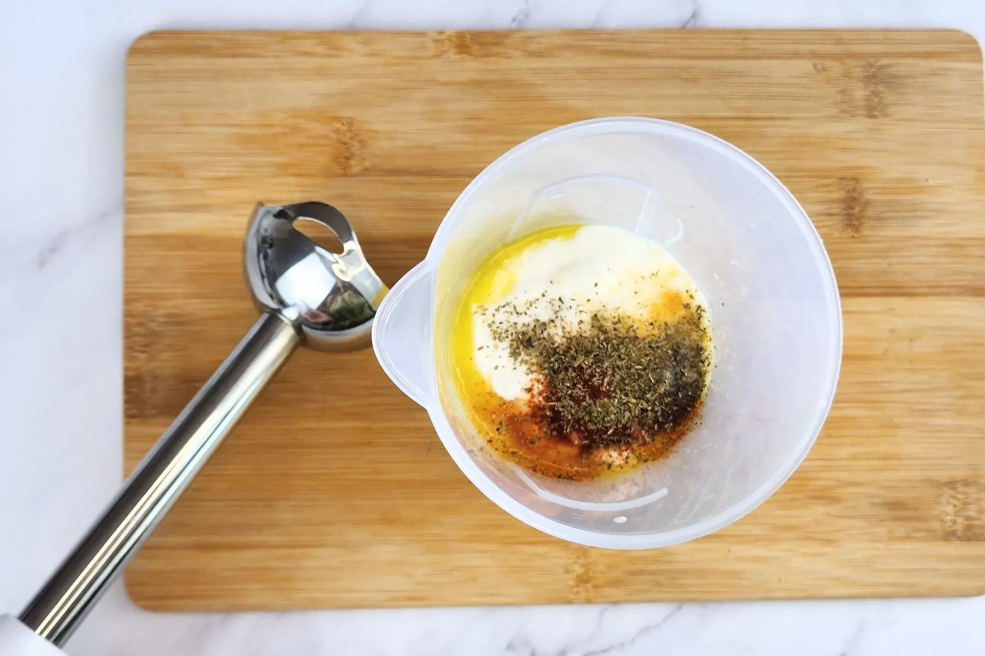 A hand  blender is next to a jar of ingredients