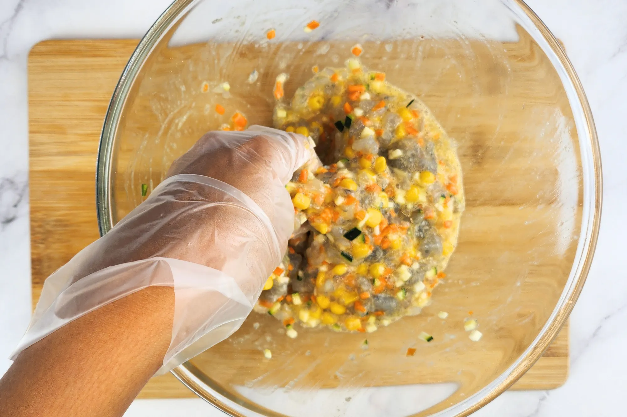 A hand in mixing bowl with Shrimp Fritters