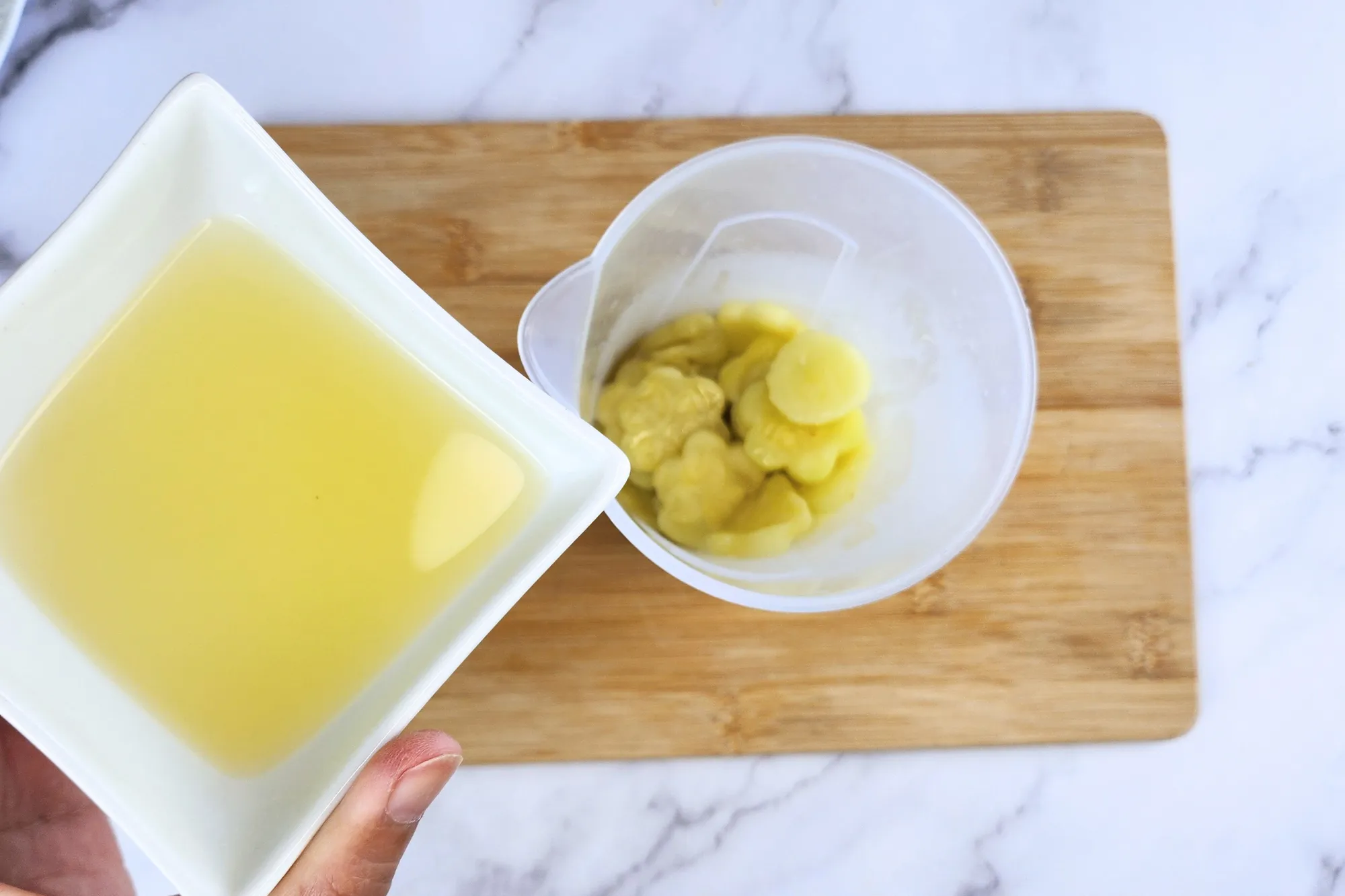 A hand is holding a bowl of lemon juice of a jar of cooked center of zucchini
