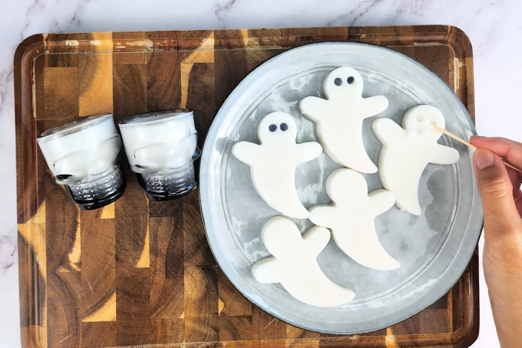 A hand is holding a toothpick to make holes on white ghost jelly