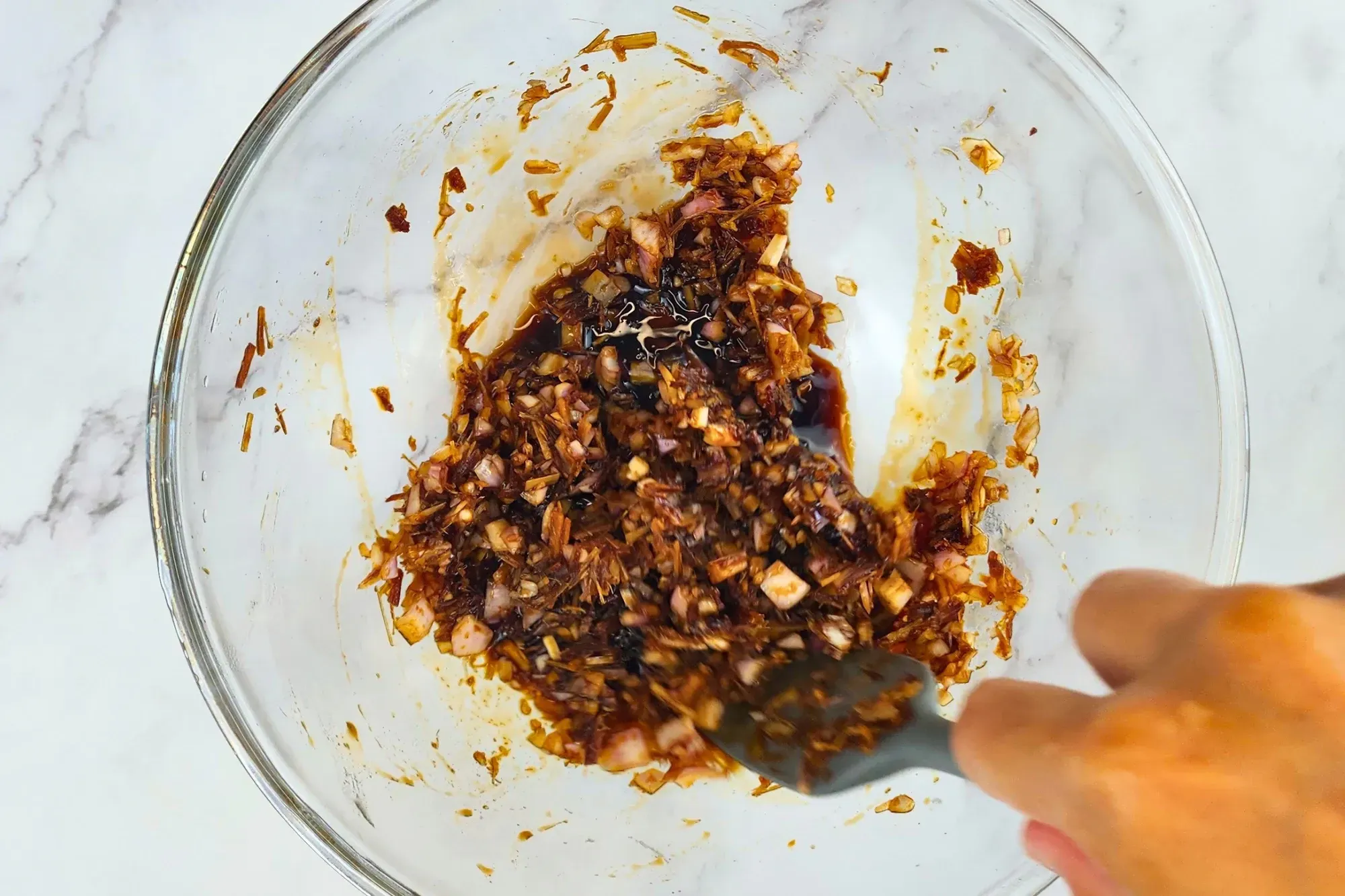 A hand mixes ingredients in a mixing bowl