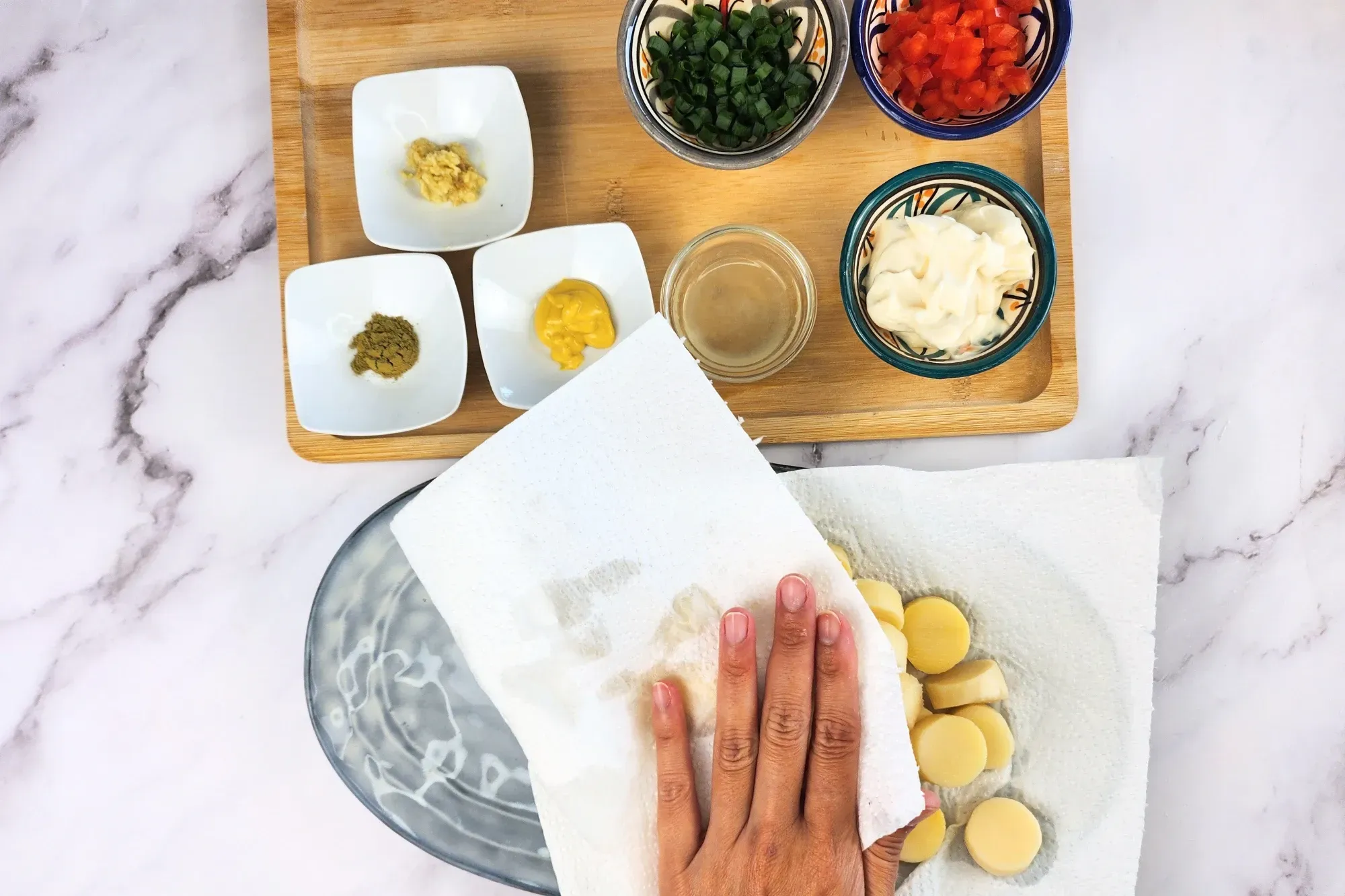 A hand presses paper towels over sliced hearts of palm on a plate to absorb moisture