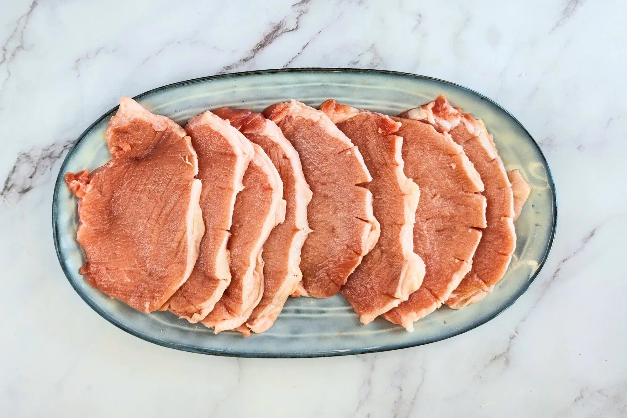 A plate full of raw pork chops