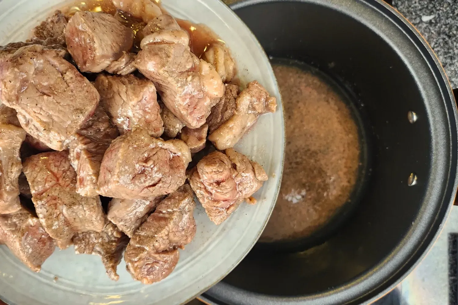 A plate of cooked meat above a cooking pot.