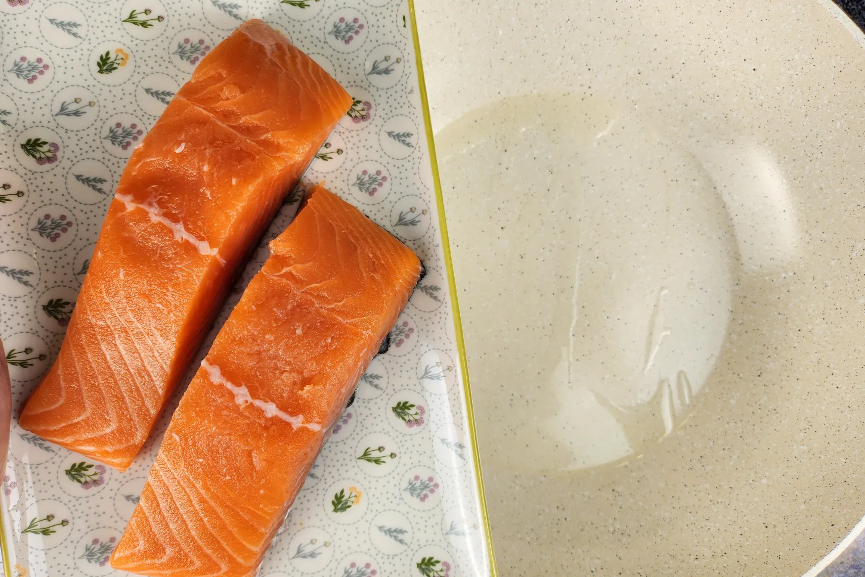 A plate of salmon fillets above a wok