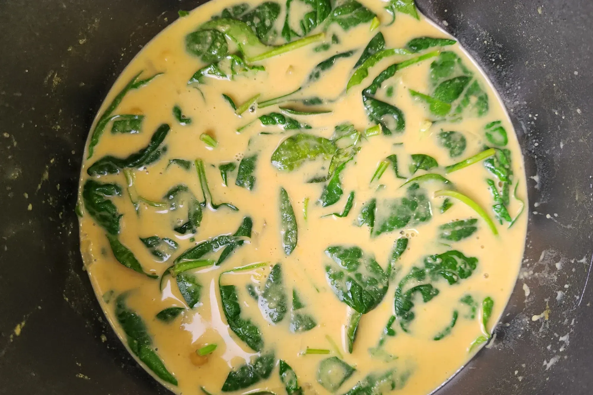 A pot with baby spinach in creamy soup