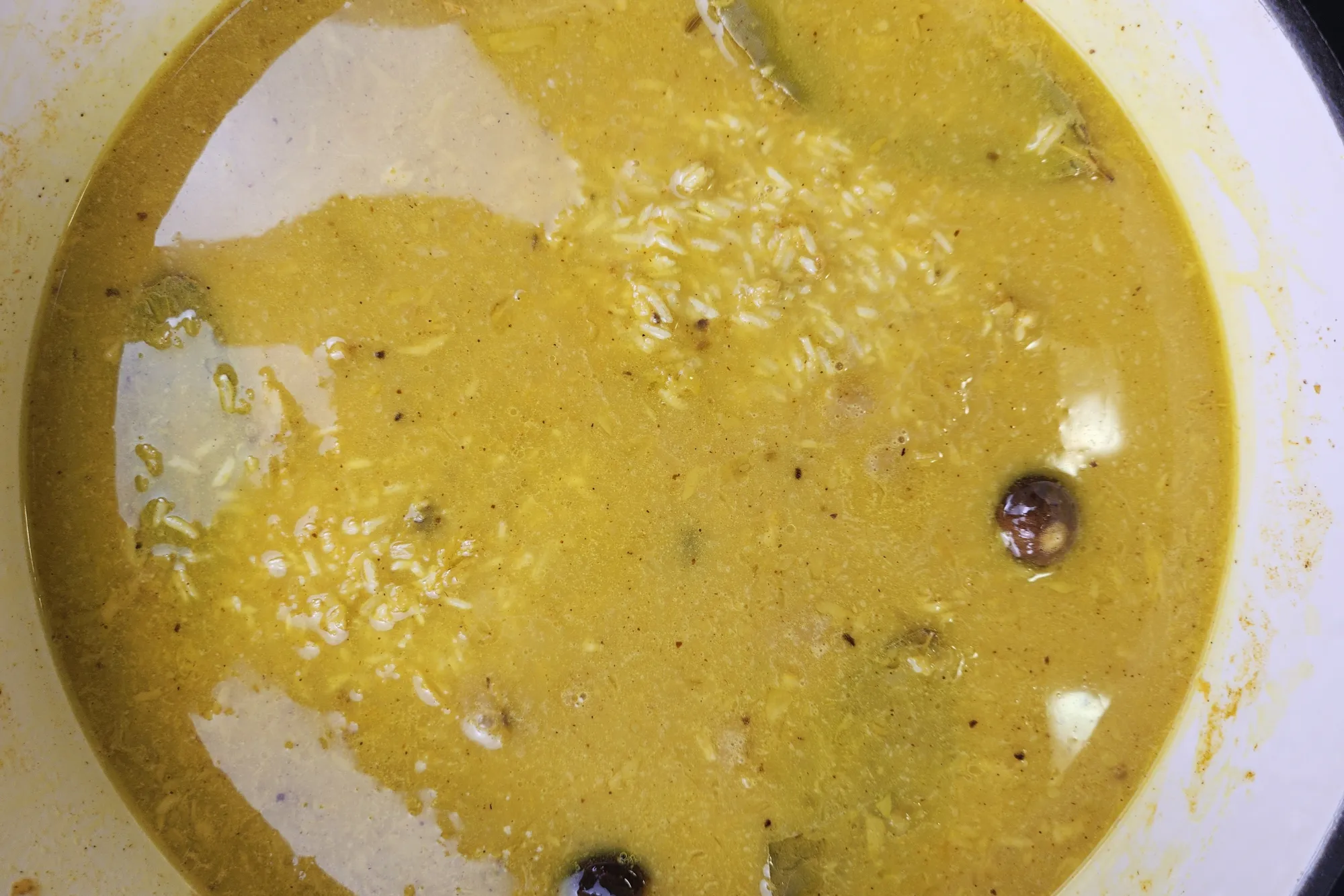 A pot with yellow liquid and rice.