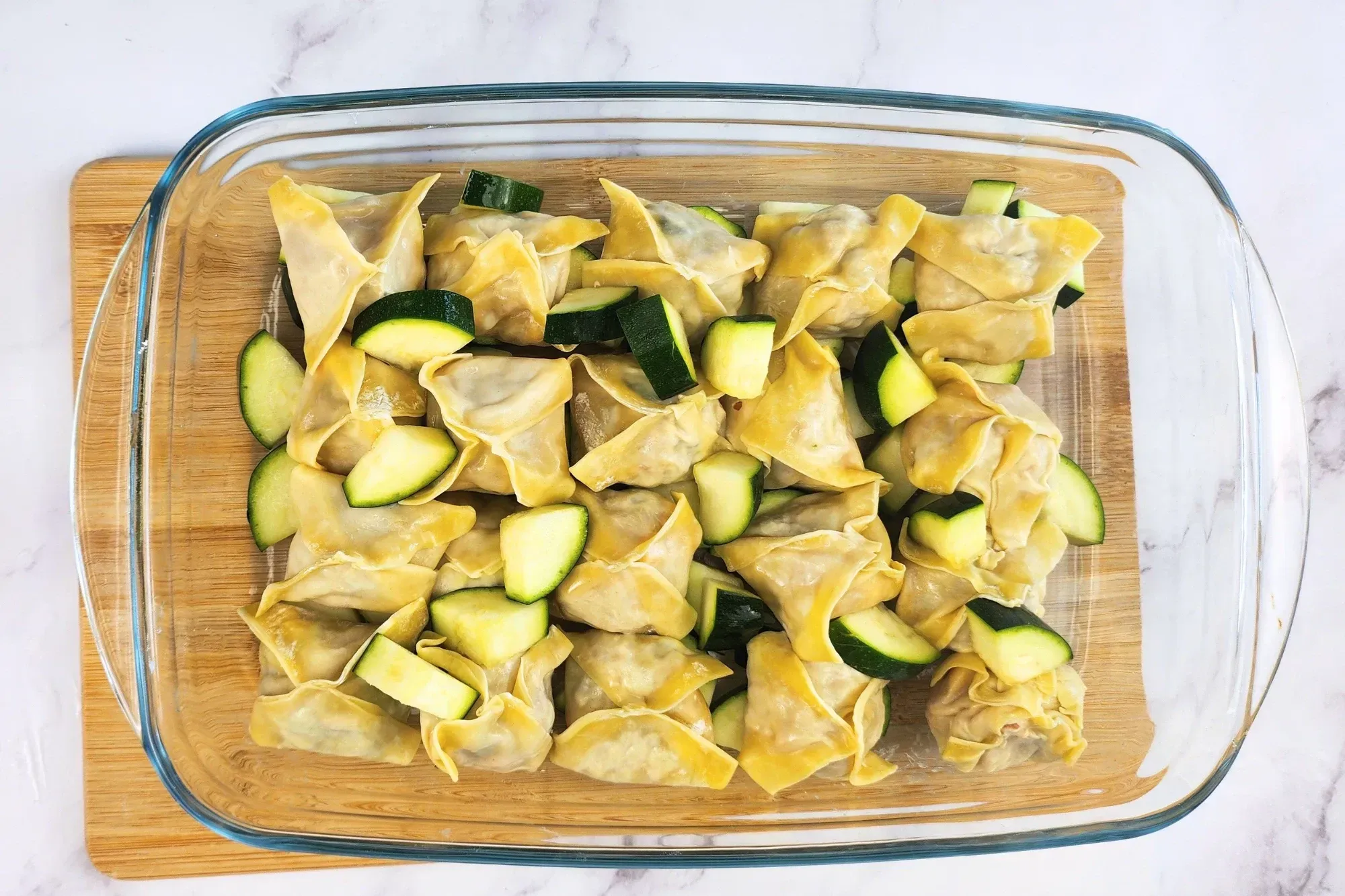 A tray of dumplings and zucchini on a wooden board.