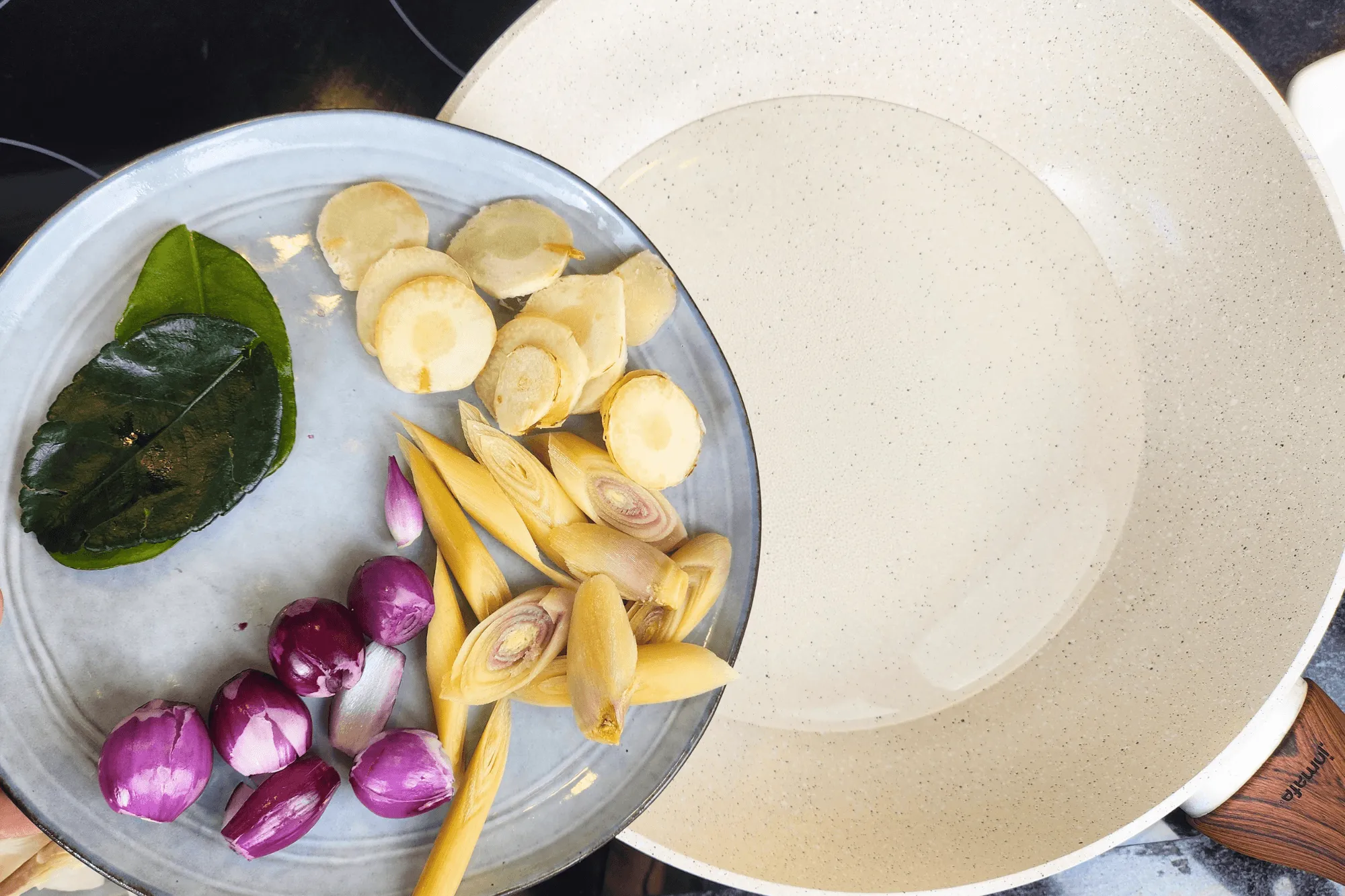 In a pot, bring water to a gentle boil. Add the galangal, lemongrass, shallots, and kaffir lime leaves. Simmer for a few minutes to infuse the water with the aromatic flavors.