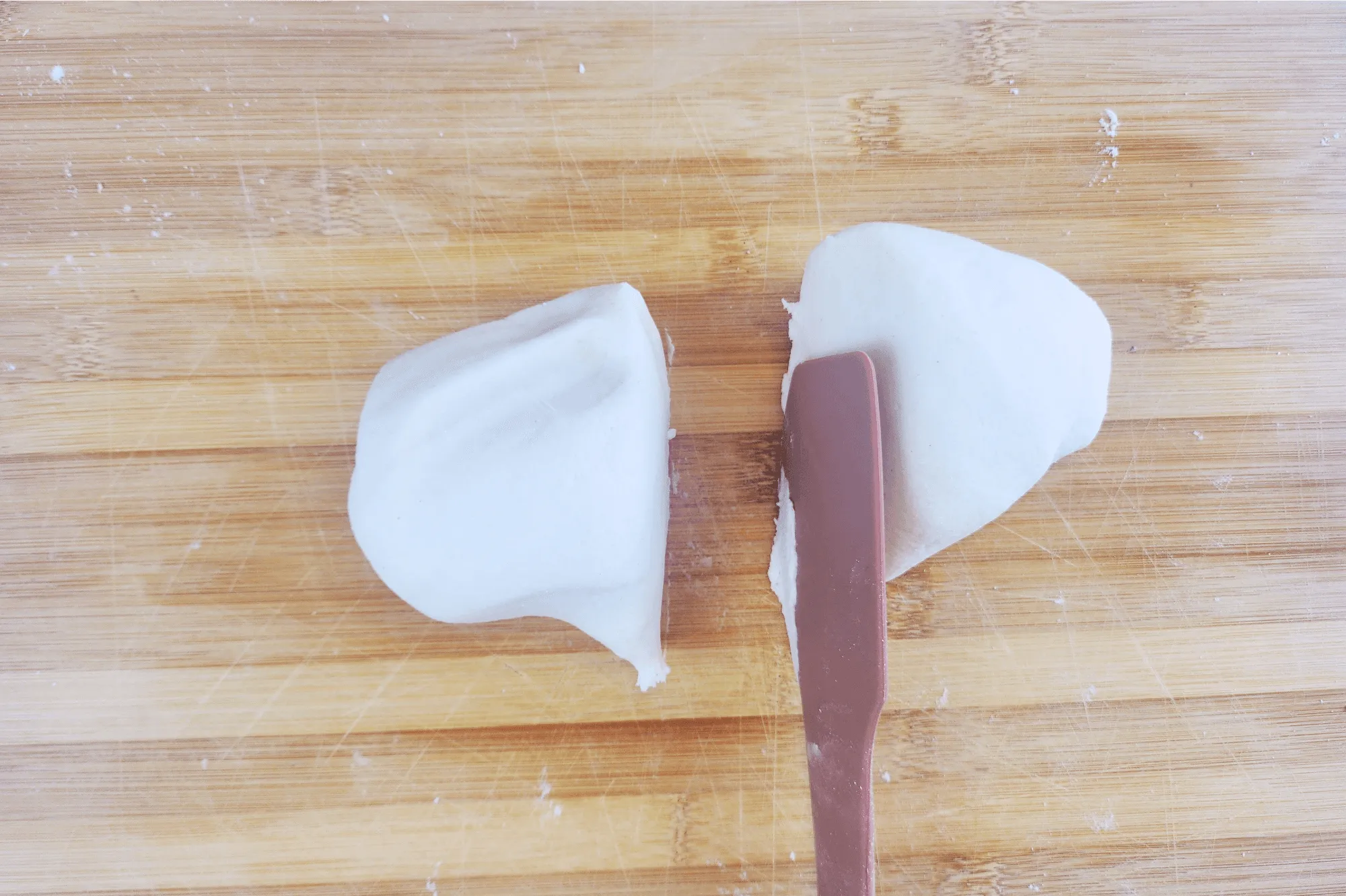 After kneading, cut the dough in half using a dough scraper 