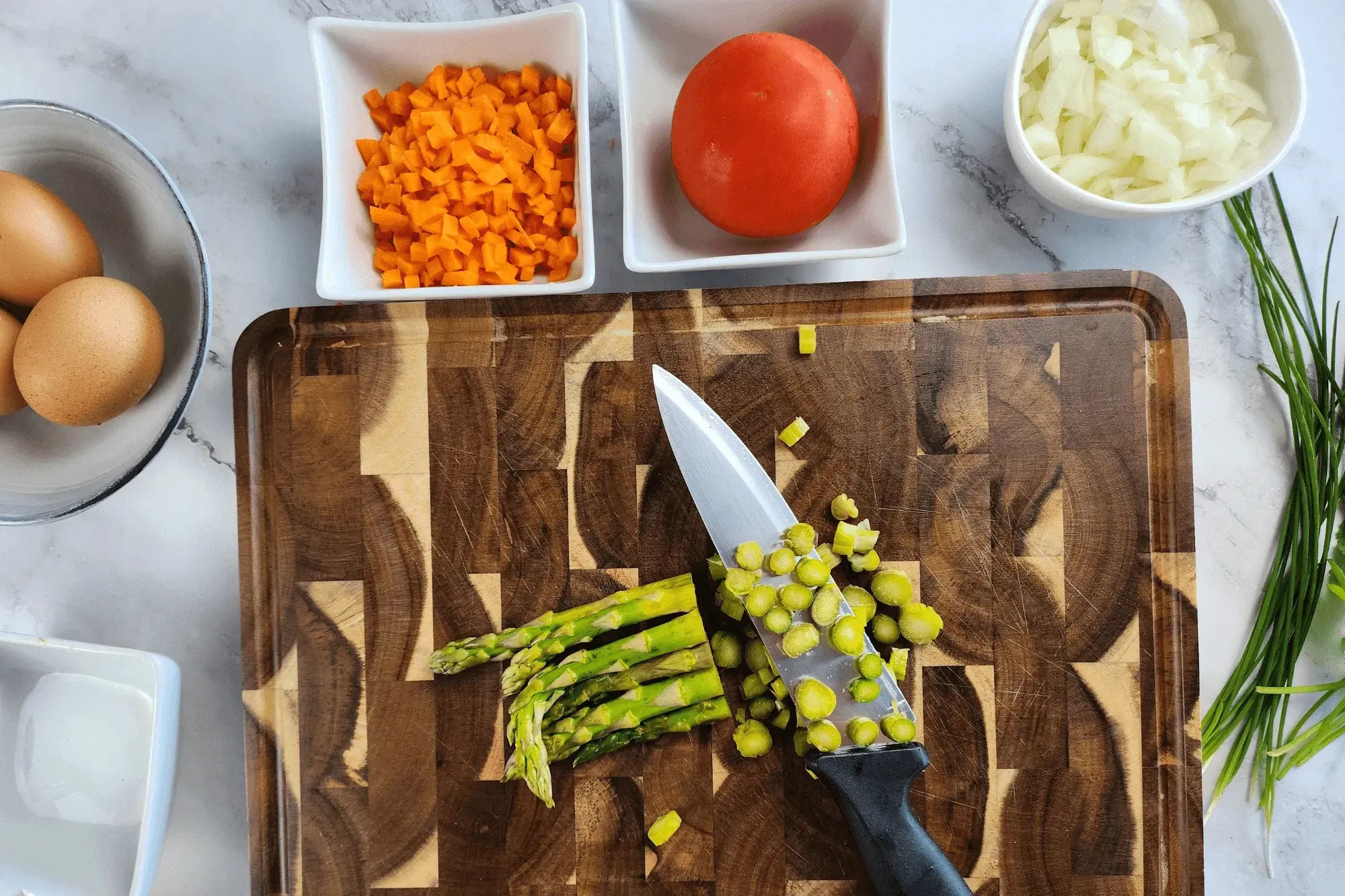 Chop the onion, carrot, asparagus, scallion, coriander and tomato into small pieces.