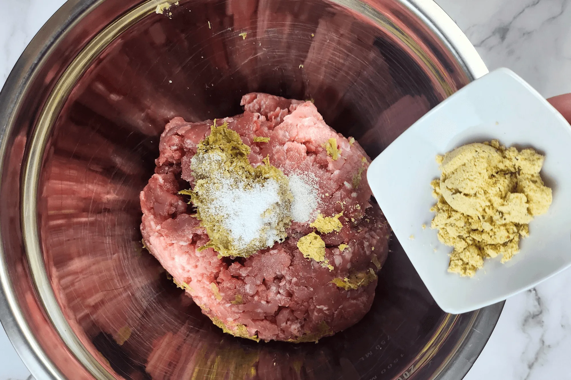 Combine the ground pork with the pounded garlic, pepper, and coriander root mixture, then season with salt, seasoning powder, and sugar. Mix and knead the ingredients for about 5 minutes until the mixture becomes slightly sticky.