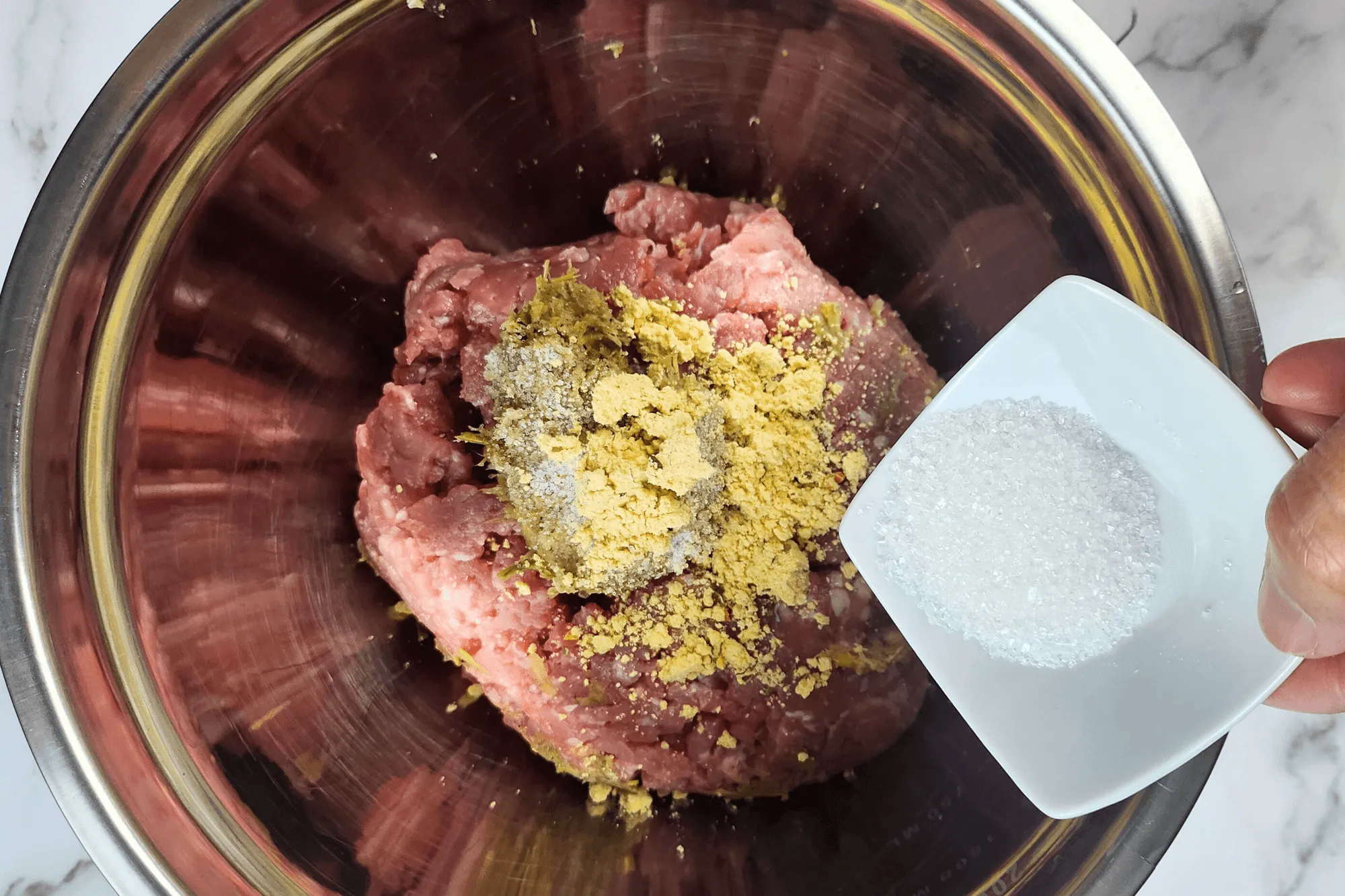 Combine the ground pork with the pounded garlic, pepper, and coriander root mixture, then season with salt, seasoning powder, and sugar. Mix and knead the ingredients for about 5 minutes until the mixture becomes slightly sticky.