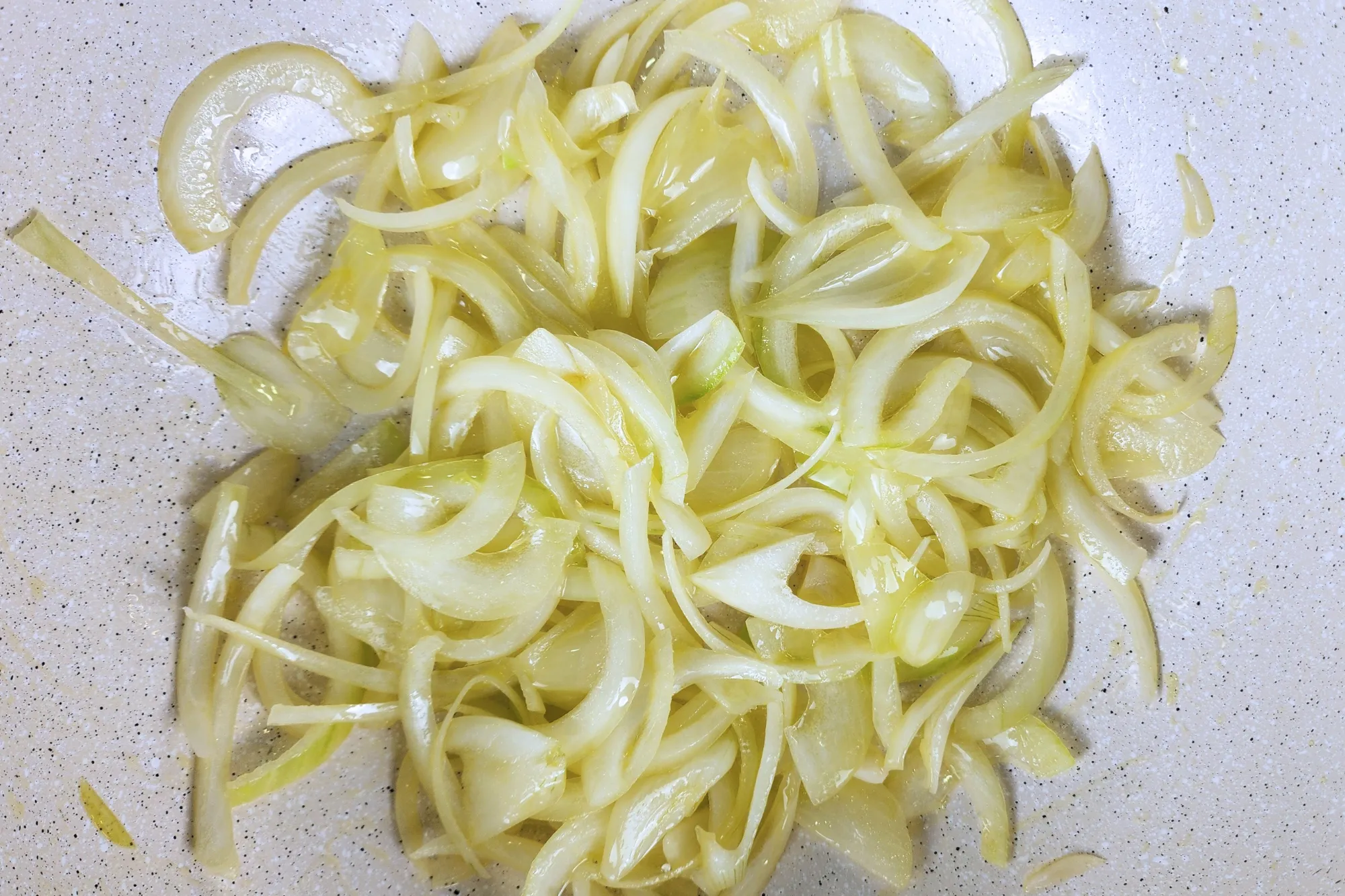 Cooked sliced onion in a wok.