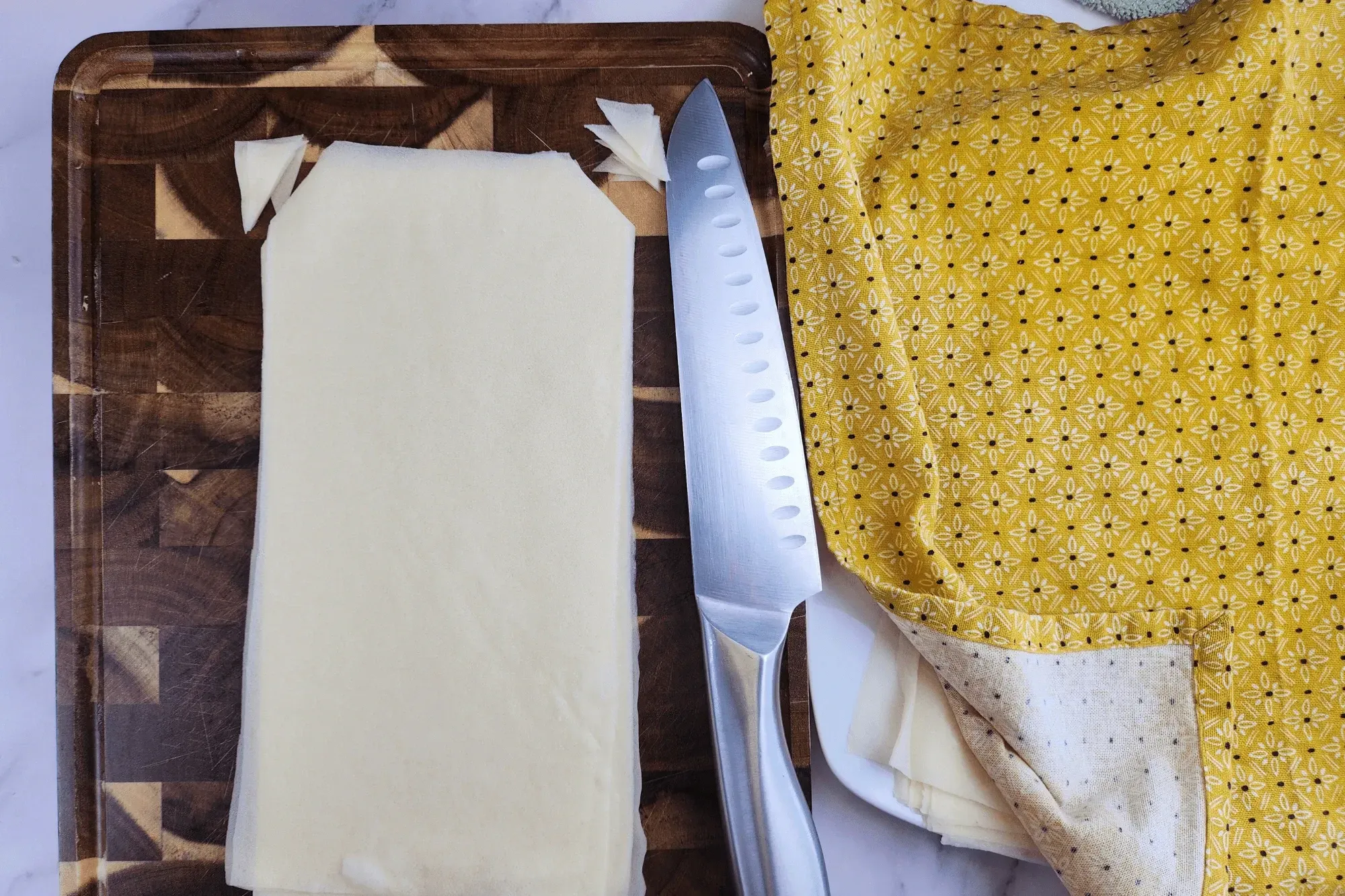 Cut a spring roll wrapper in half, then trim the top corner to form a small triangle shape.