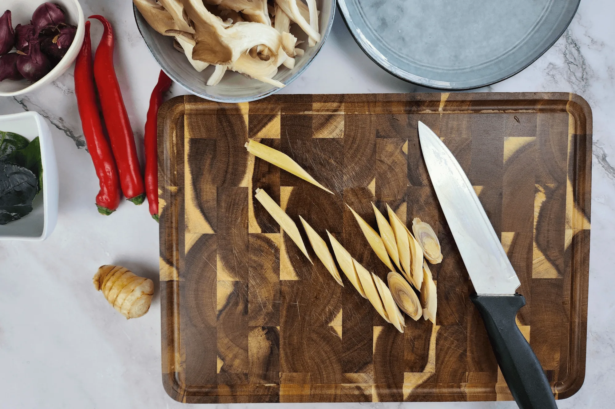 Trim the roots or stems of the oyster mushrooms and tear them into bite-sized pieces. Cut the lemongrass diagonally into short or long sections, then bruise it lightly using a pestle or the back of a knife to release its aroma. Slice the young galangal into thin rounds. Tear the kaffir lime leaves by hand. Peel the shallots and crush them gently to release their flavor.