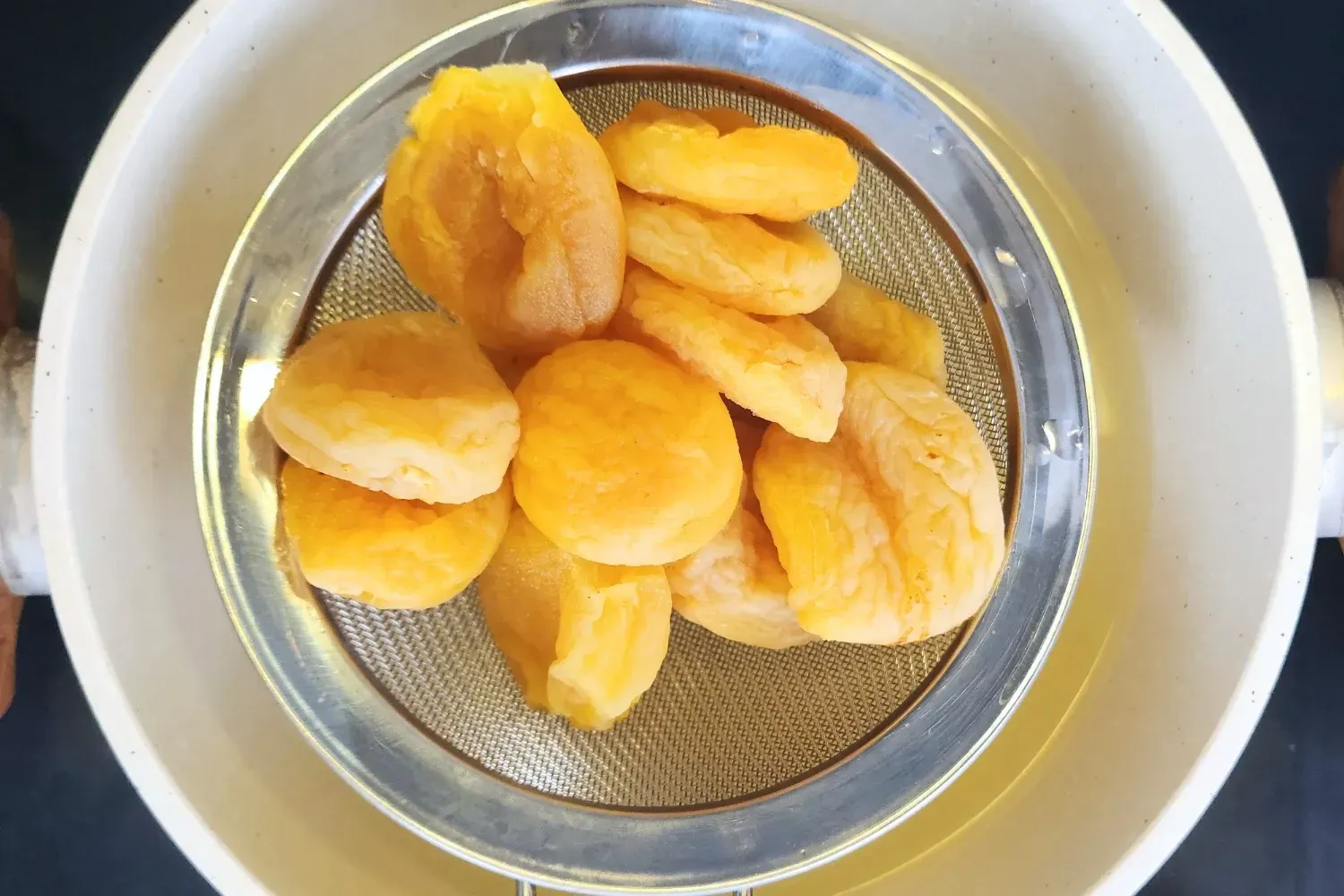 Drain apricots above a pot.