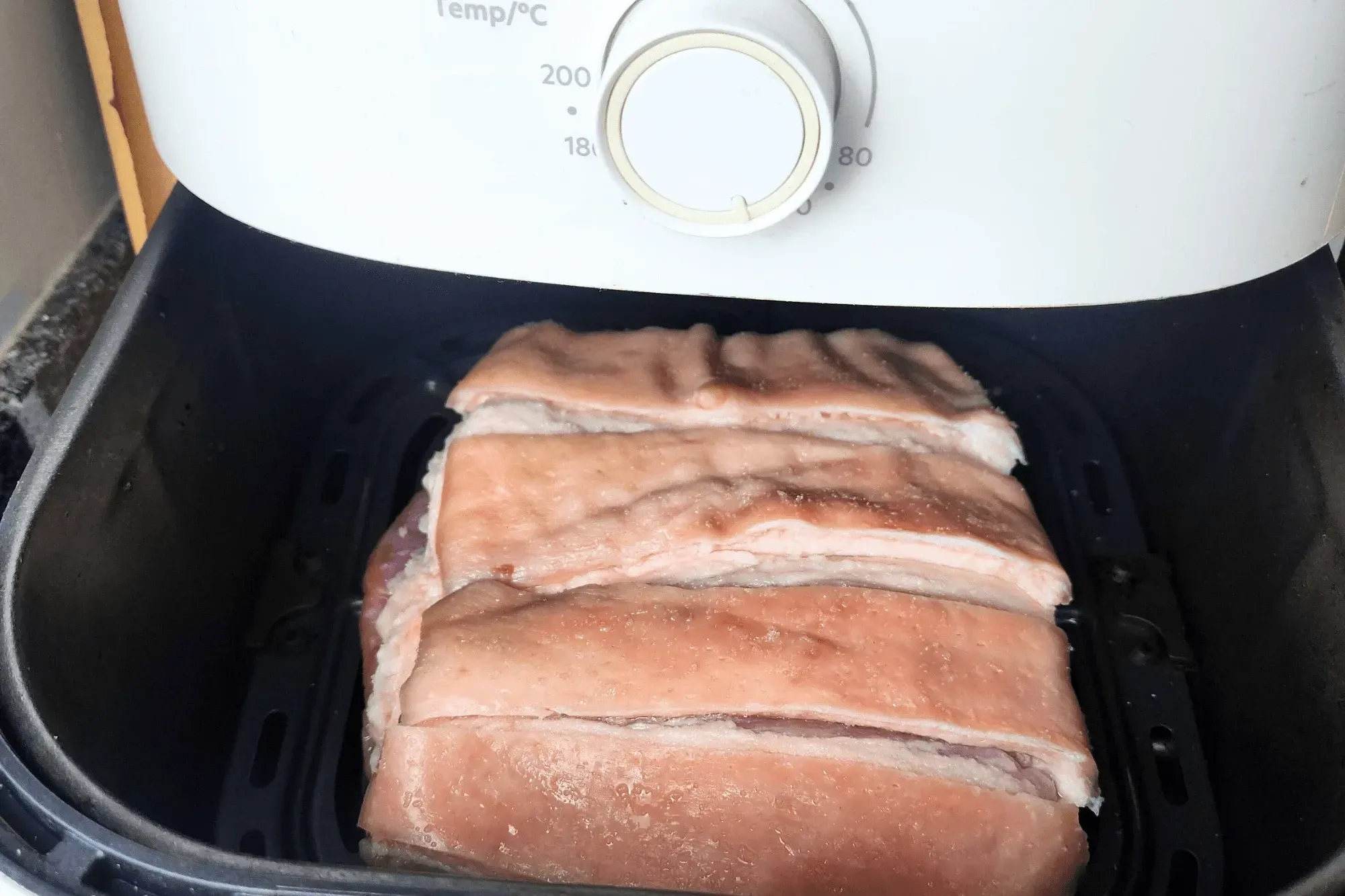 First Round: Place the pork belly skin side up in the air fryer. Set at 100°C (212°F) for 20 minutes.