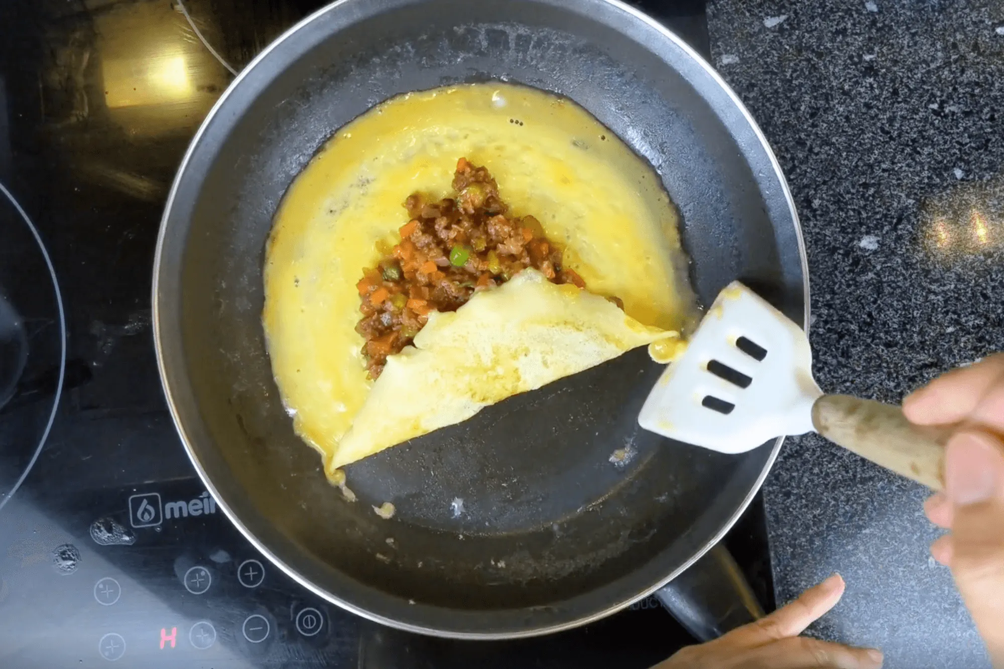 Fold the omelette over the filling to form a neat square, enclosing the filling. You can turn off the heat in this step.