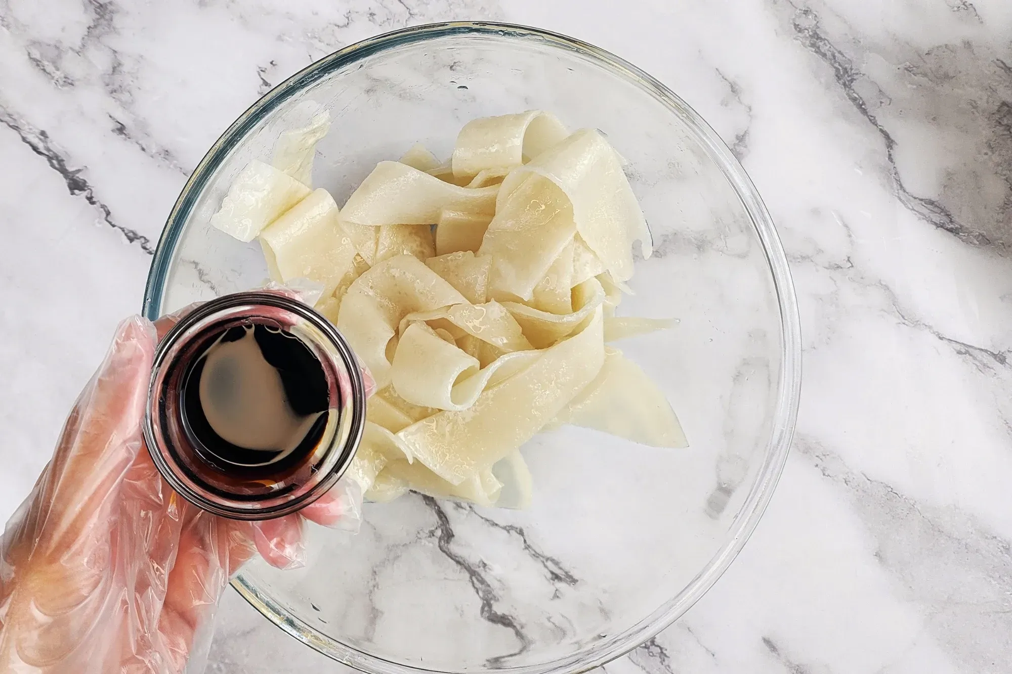 In a separate bowl, combine the wide rice noodles with black soy sauce