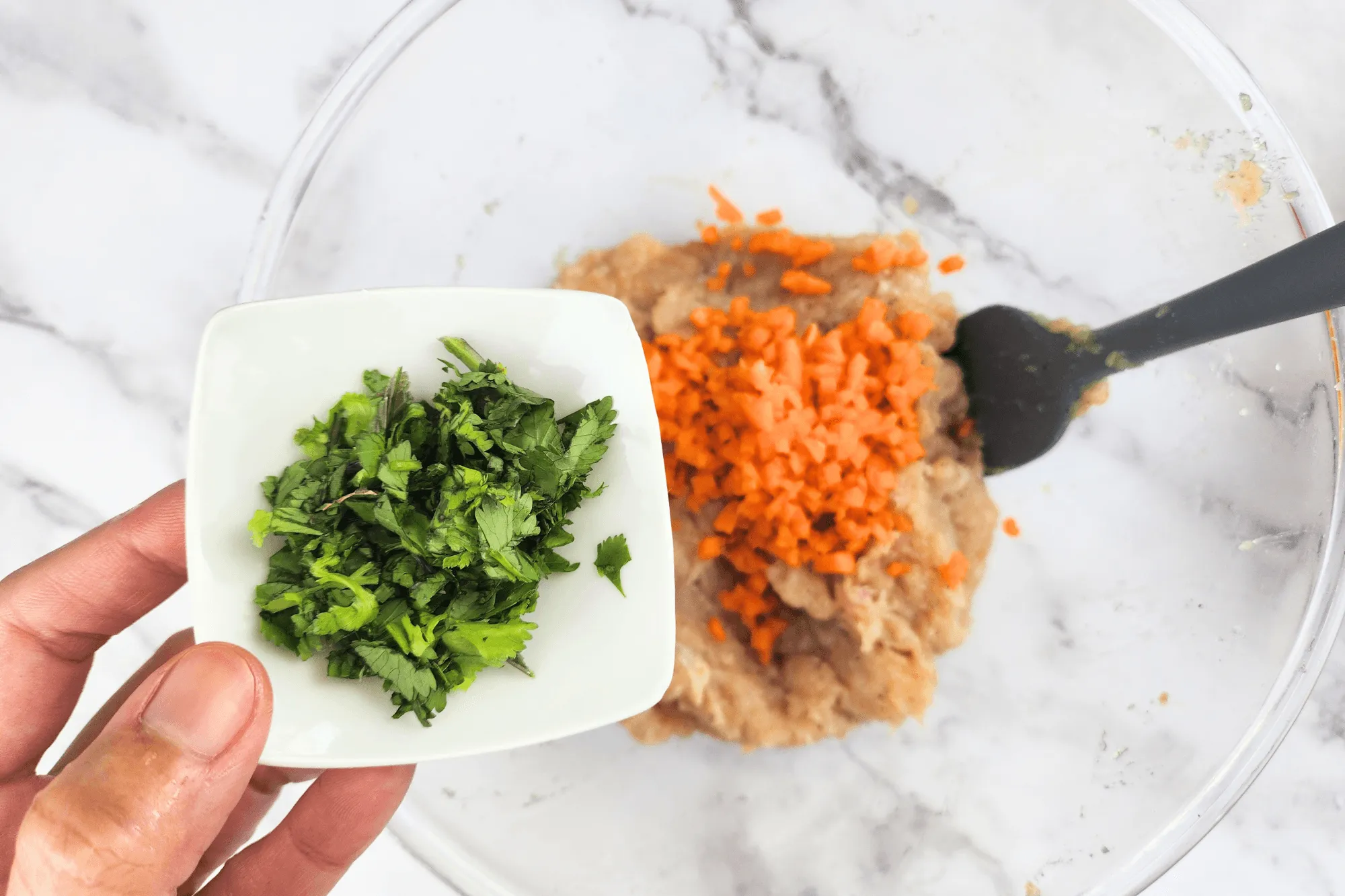 Mix ground chicken, minced garlic, black pepper, oyster sauce, soy sauce, minced carrot, and chopped coriander in a bowl.