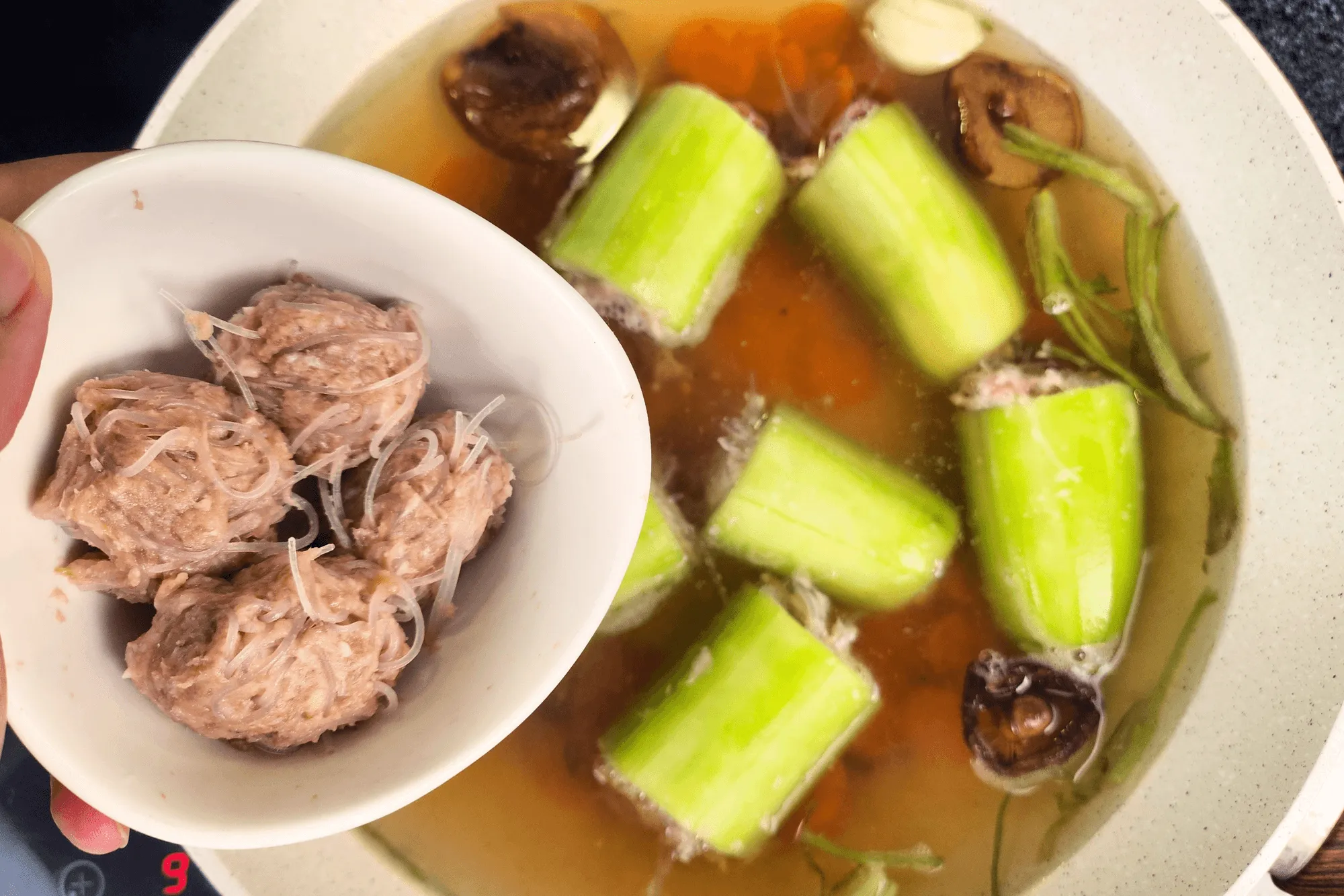 Once the broth is boiling, add the stuffed cucumbers and pork meatballs. Simmer for about 10 minutes.