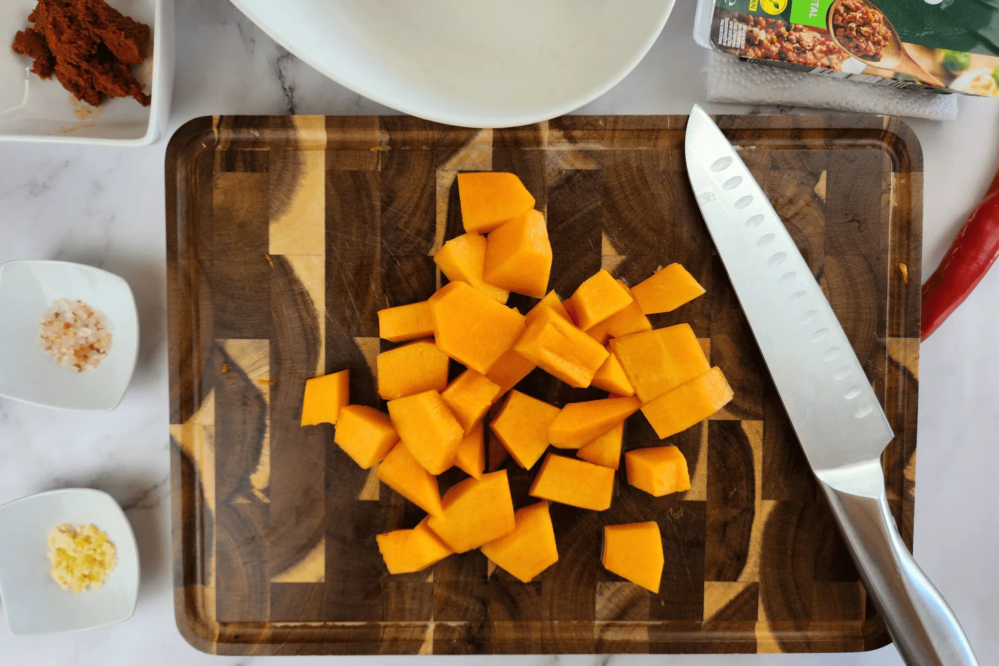 Peel the pumpkin, cut it into bite-sized pieces, and slice the red chili pepper.