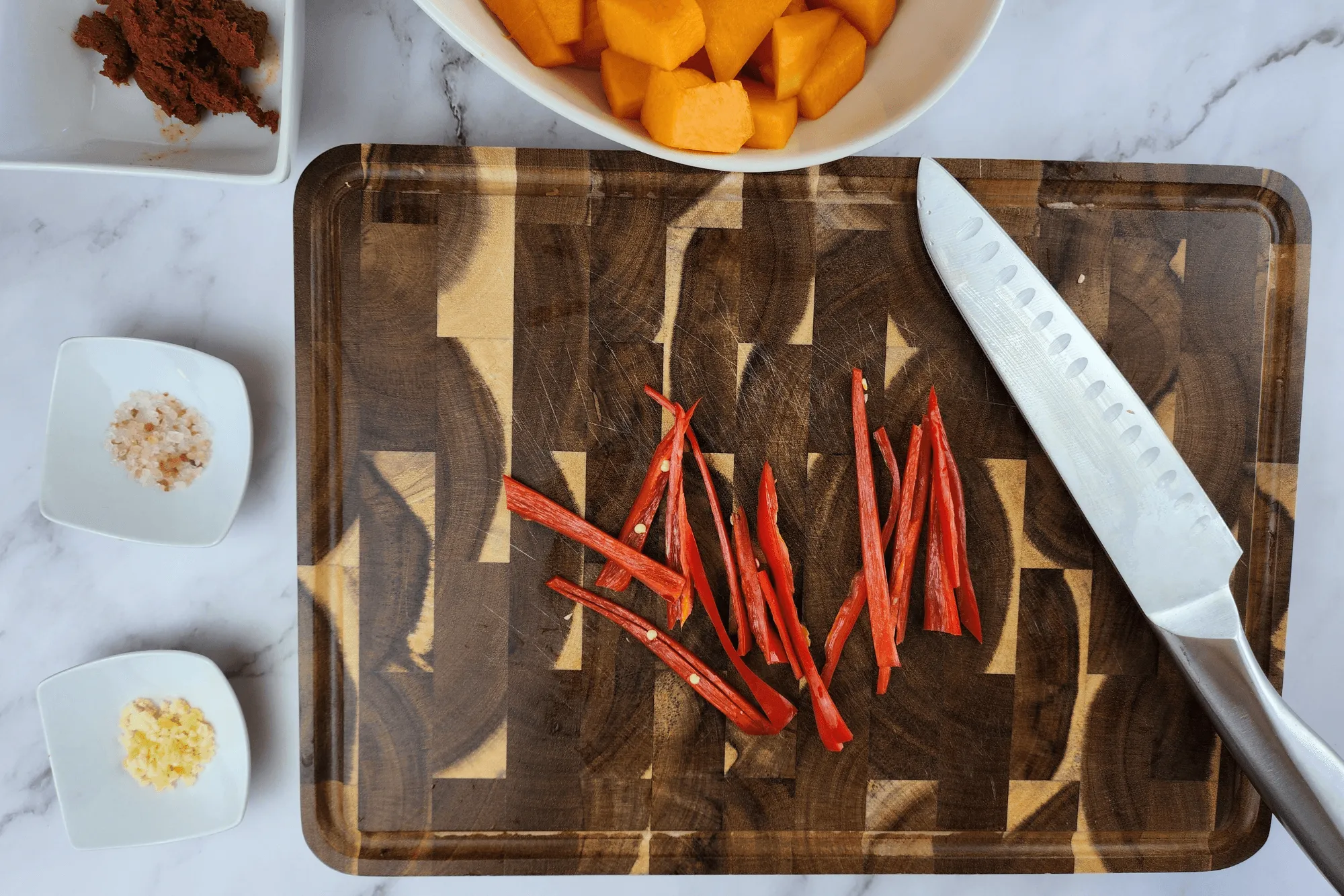 Peel the pumpkin, cut it into bite-sized pieces, and slice the red chili pepper.