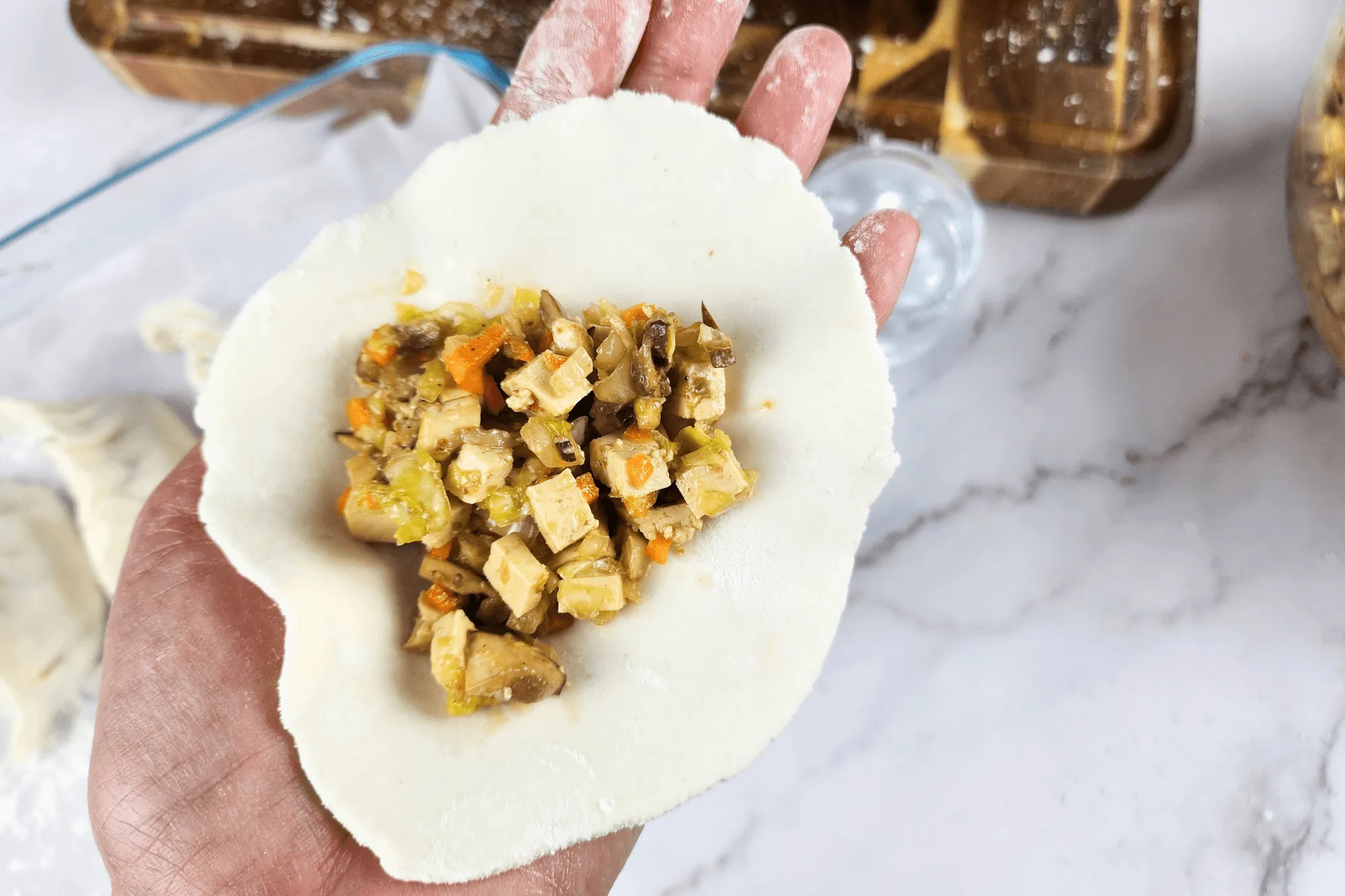 Place a gyoza wrapper on your palm, then scoop about 1 tablespoon of the vegetable filling into the center of the wrapper.