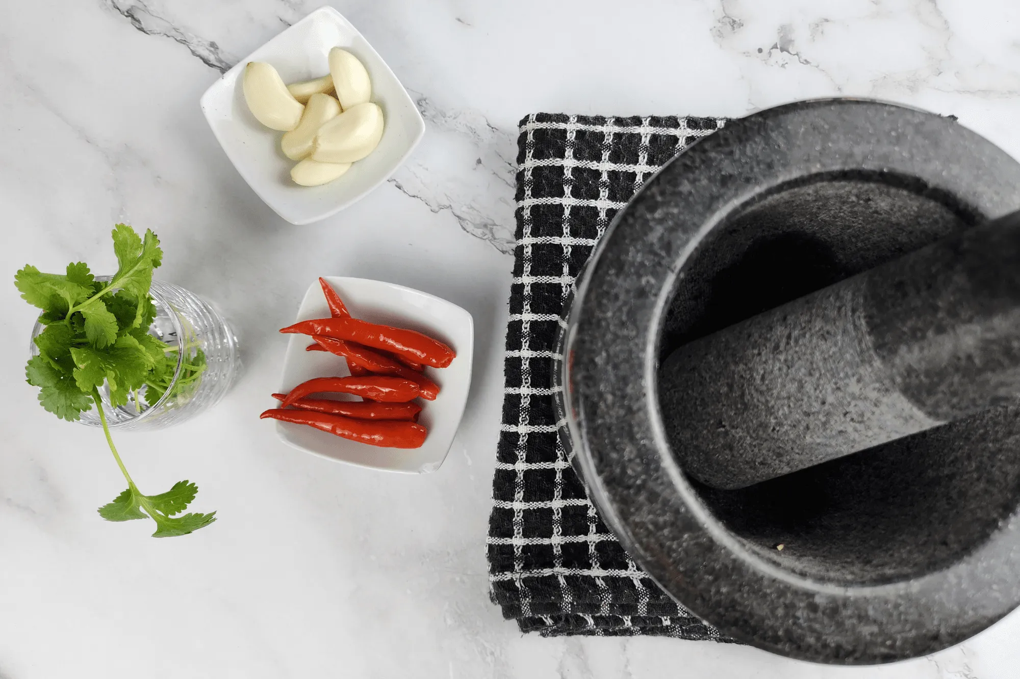 Pound the bird’s eye chili, garlic, and coriander together in a mortar and pestle until well mixed.