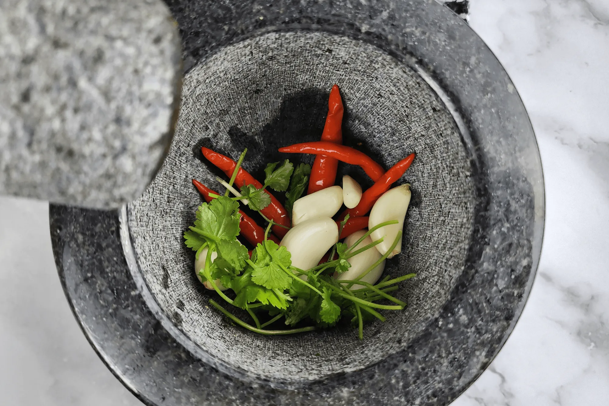 Pound the bird’s eye chili, garlic, and coriander together in a mortar and pestle until well mixed.