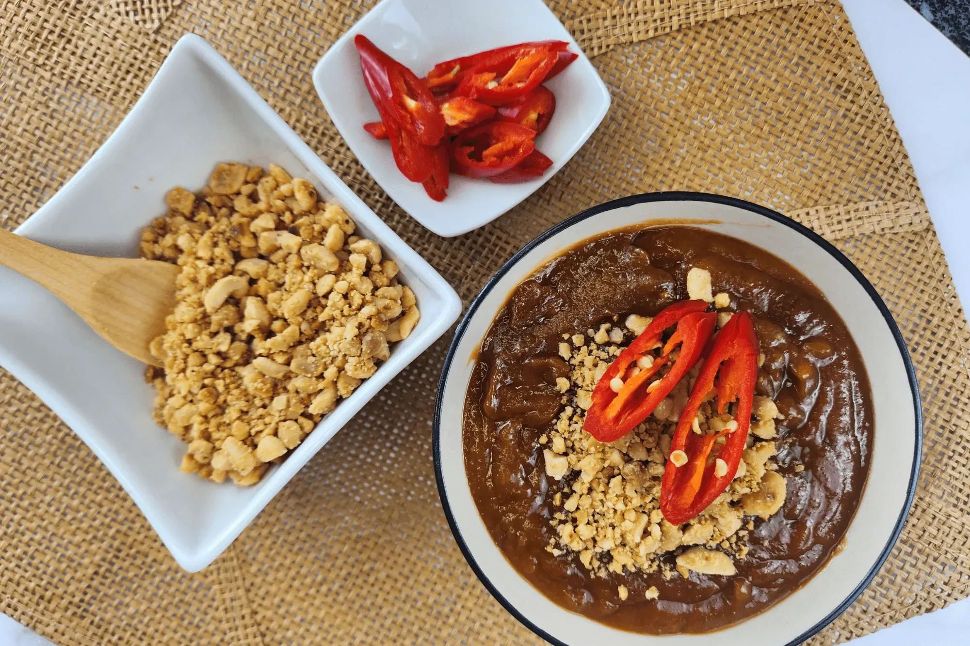 a bowl of Vietnamese Peanut Dipping Sauce, a bowl of crushed peanut and a bowl of red chili