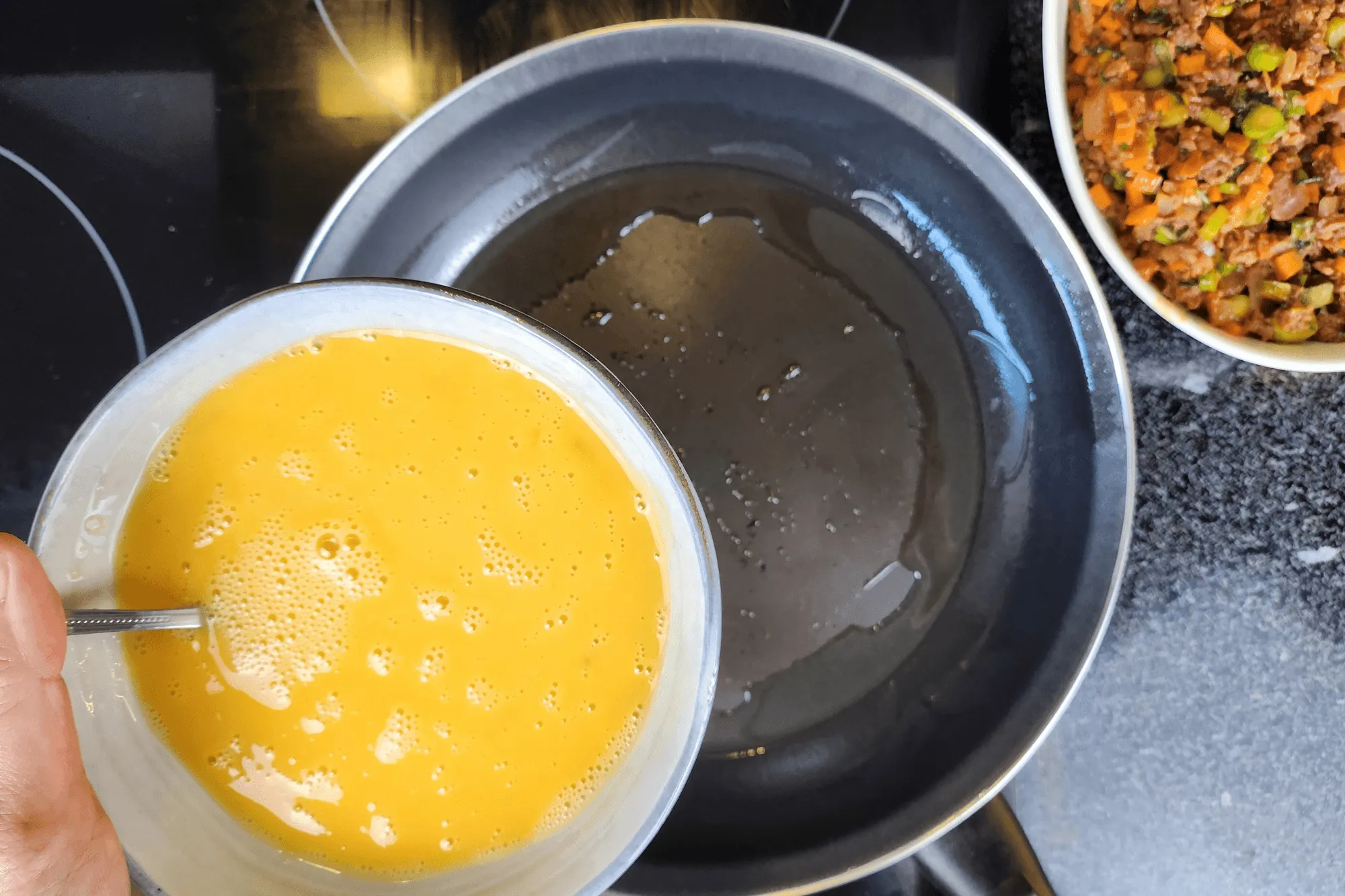 Pour the beaten eggs into the pan, tilting to spread them evenly.