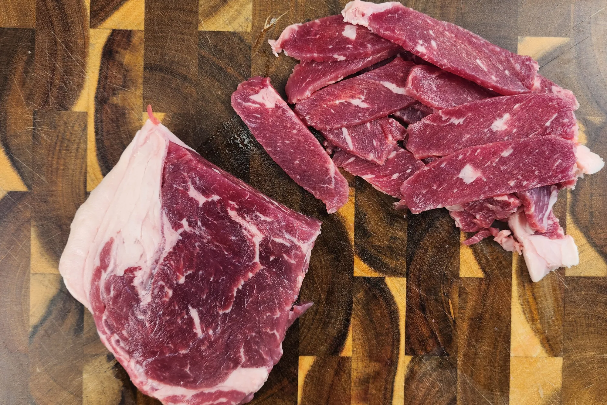 Sliced beef on a wooden board.