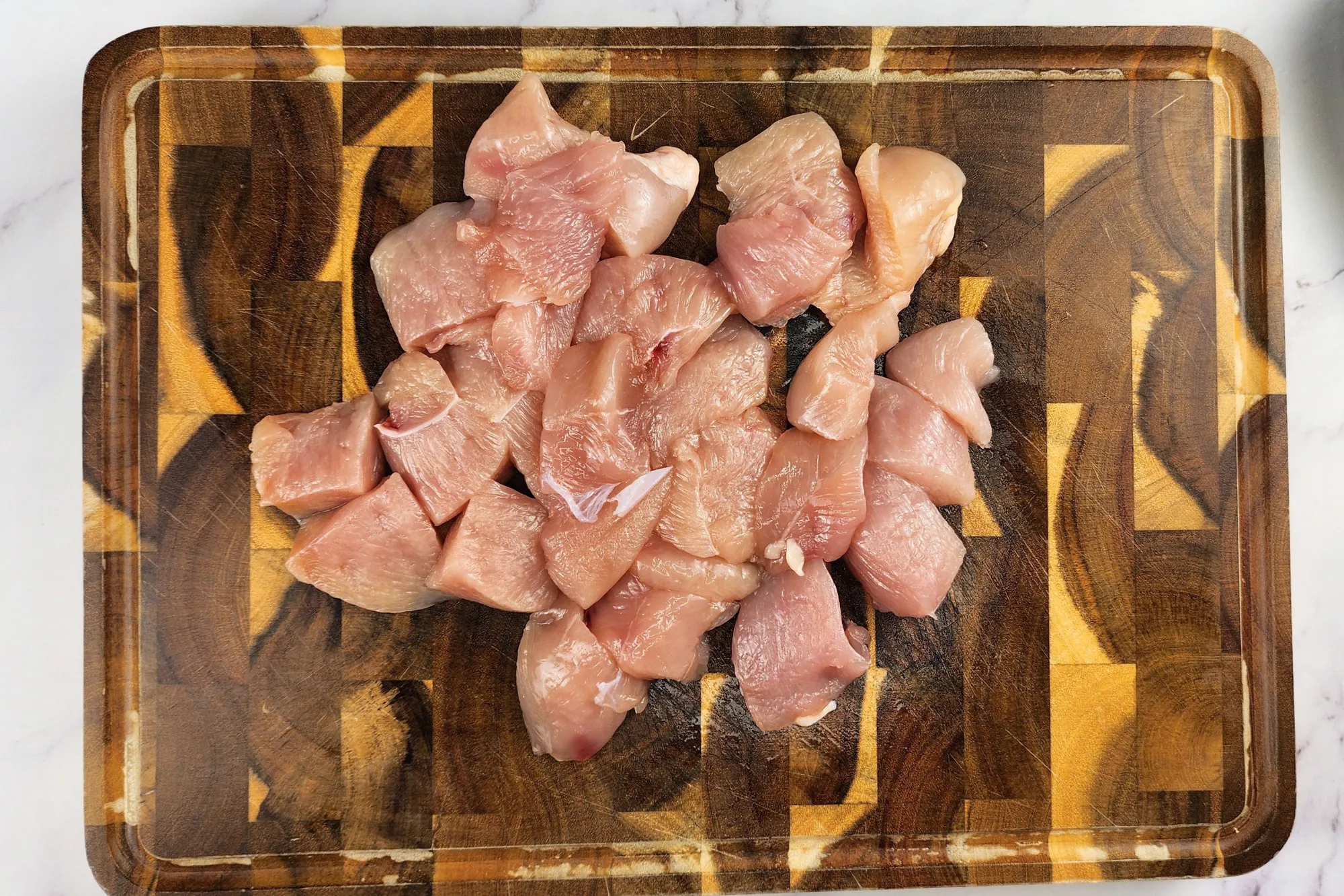 Slices of chicken breast on a wooden chopping board.