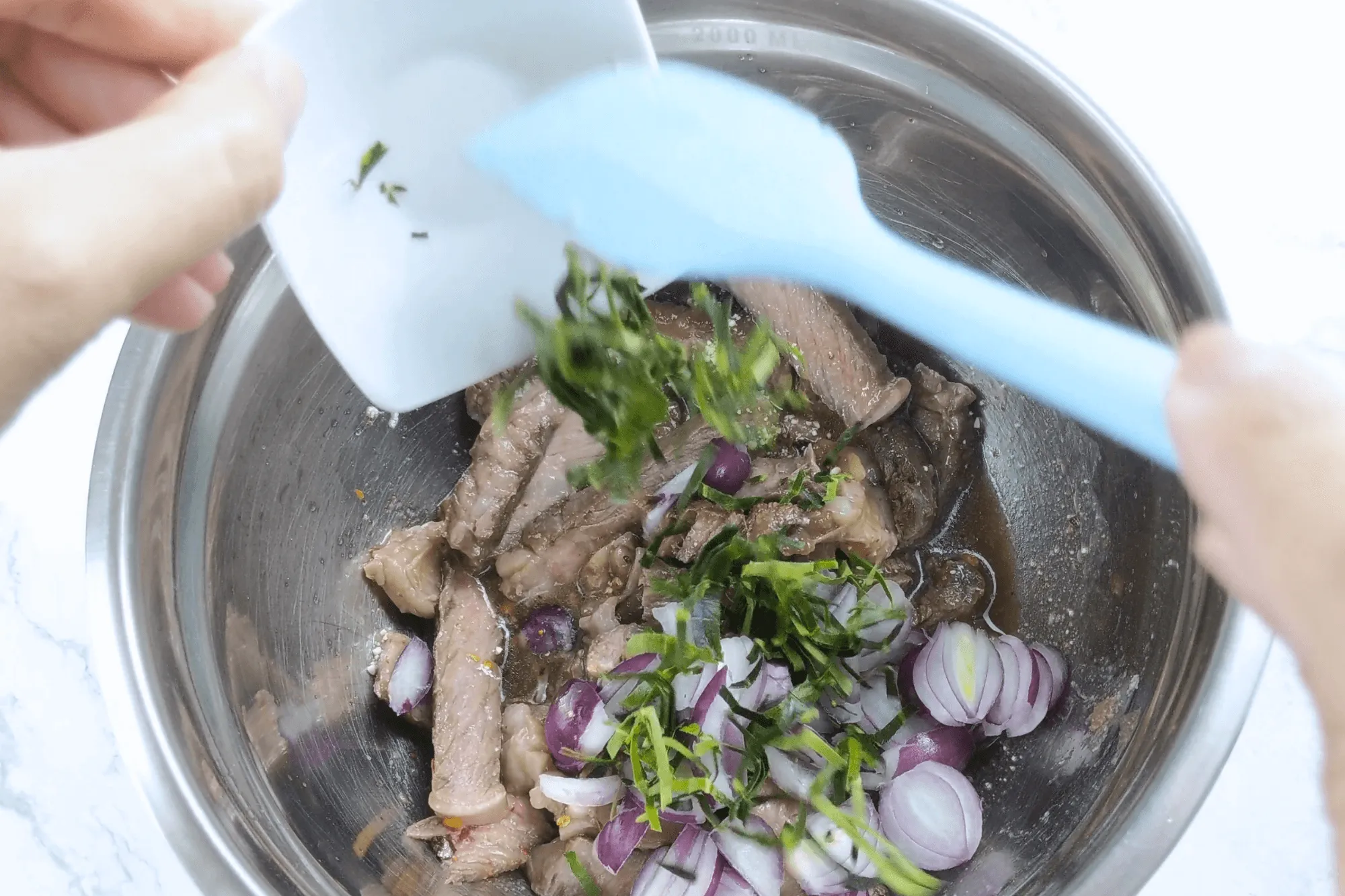 Add sliced shallots, chopped coriander, mint leaves, and sliced kaffir lime leaves. Plate and serve immediately.