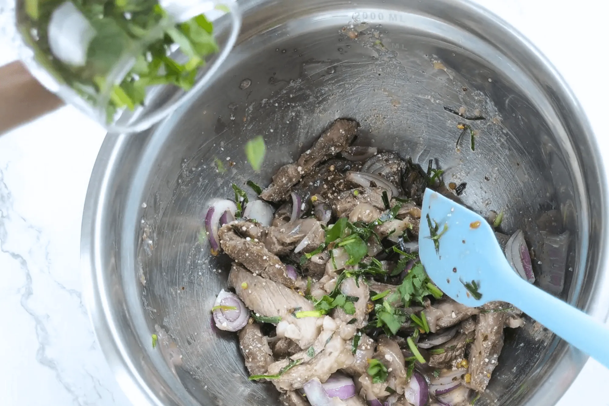 Add sliced shallots, chopped coriander, mint leaves, and sliced kaffir lime leaves. Plate and serve immediately.