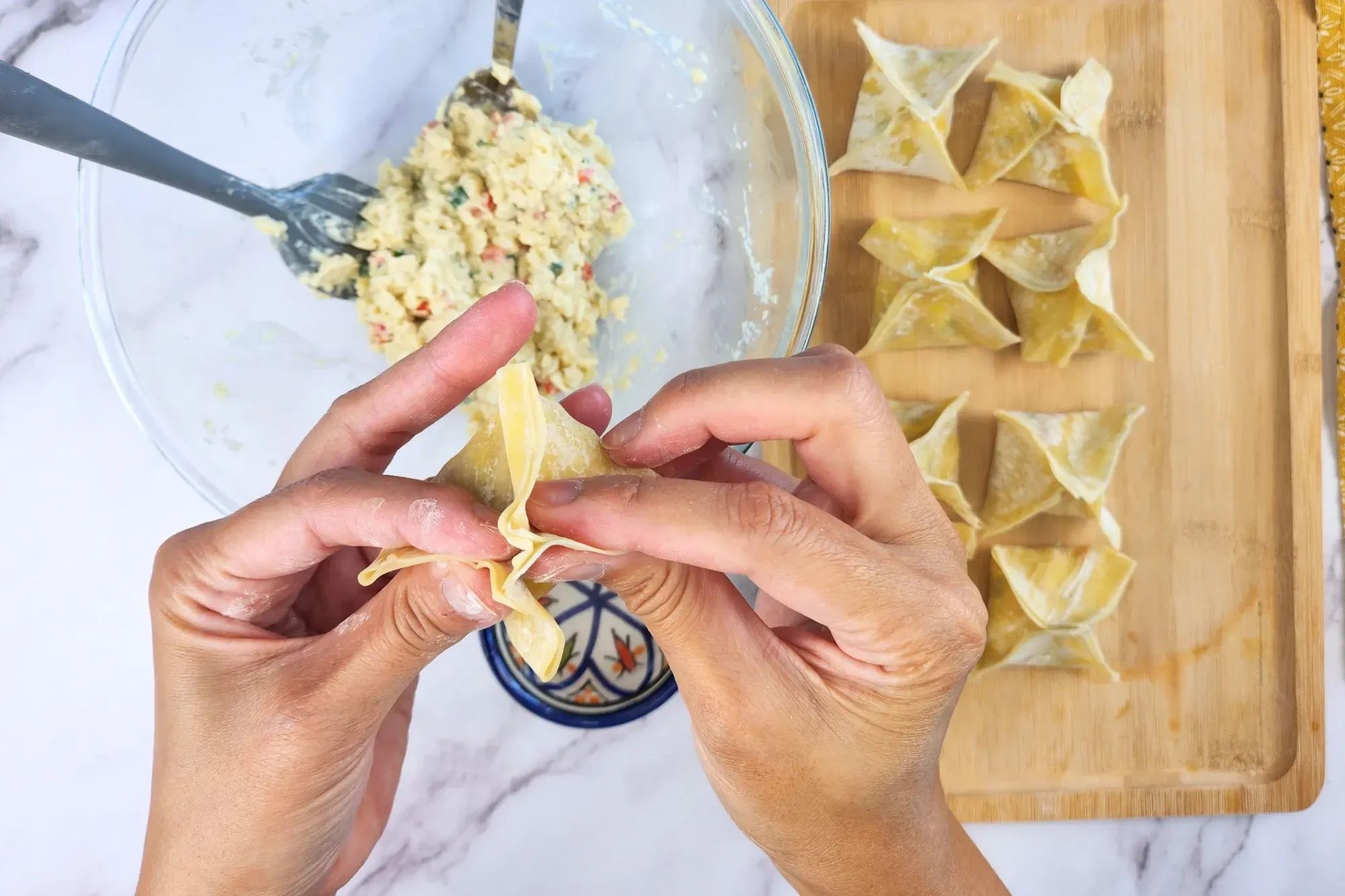 Two hands are sealing the wonton.